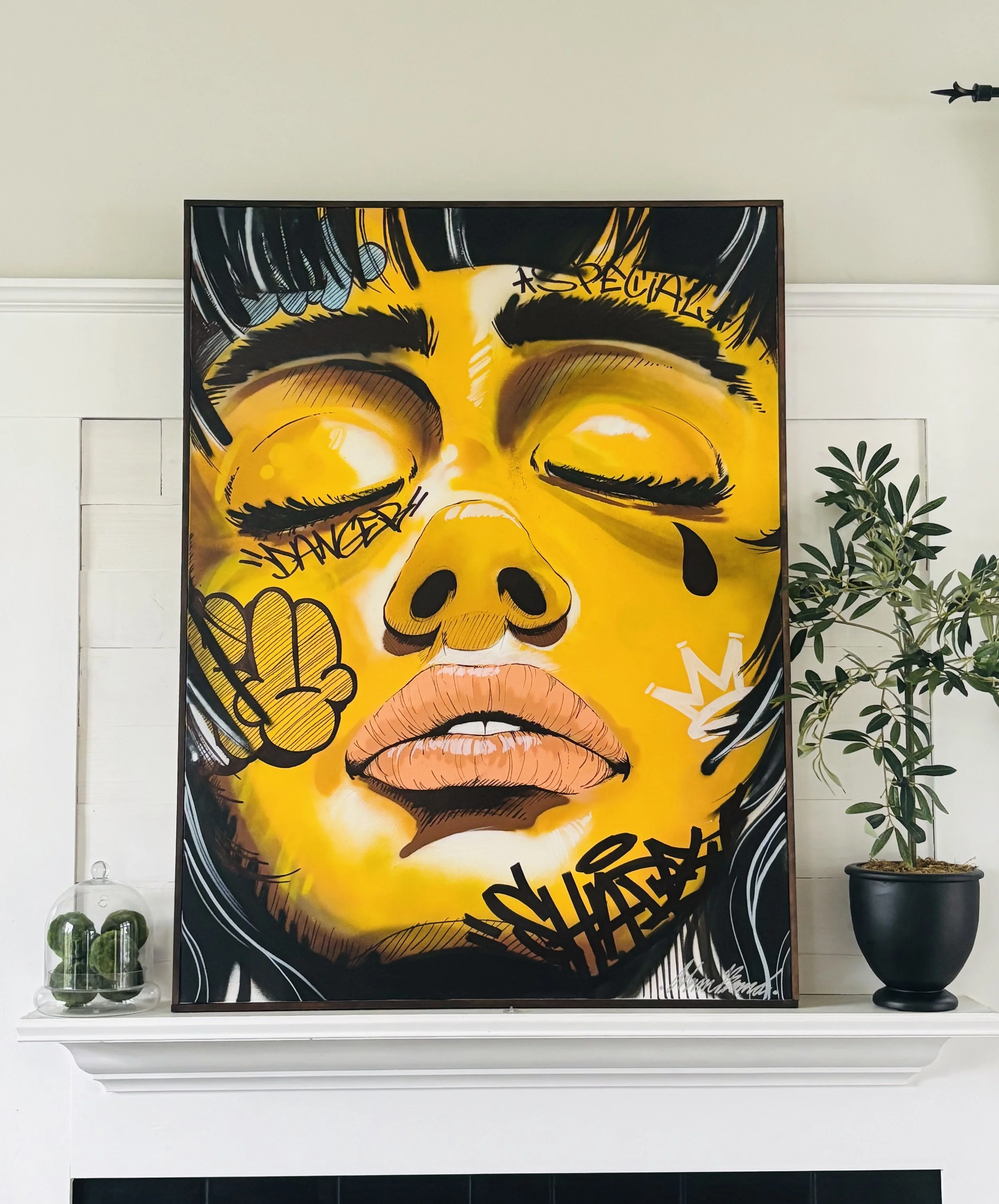 A colorful portrait of a woman's face with closed eyes, surrounded by graffiti-style text and symbols, on a black and gold background.