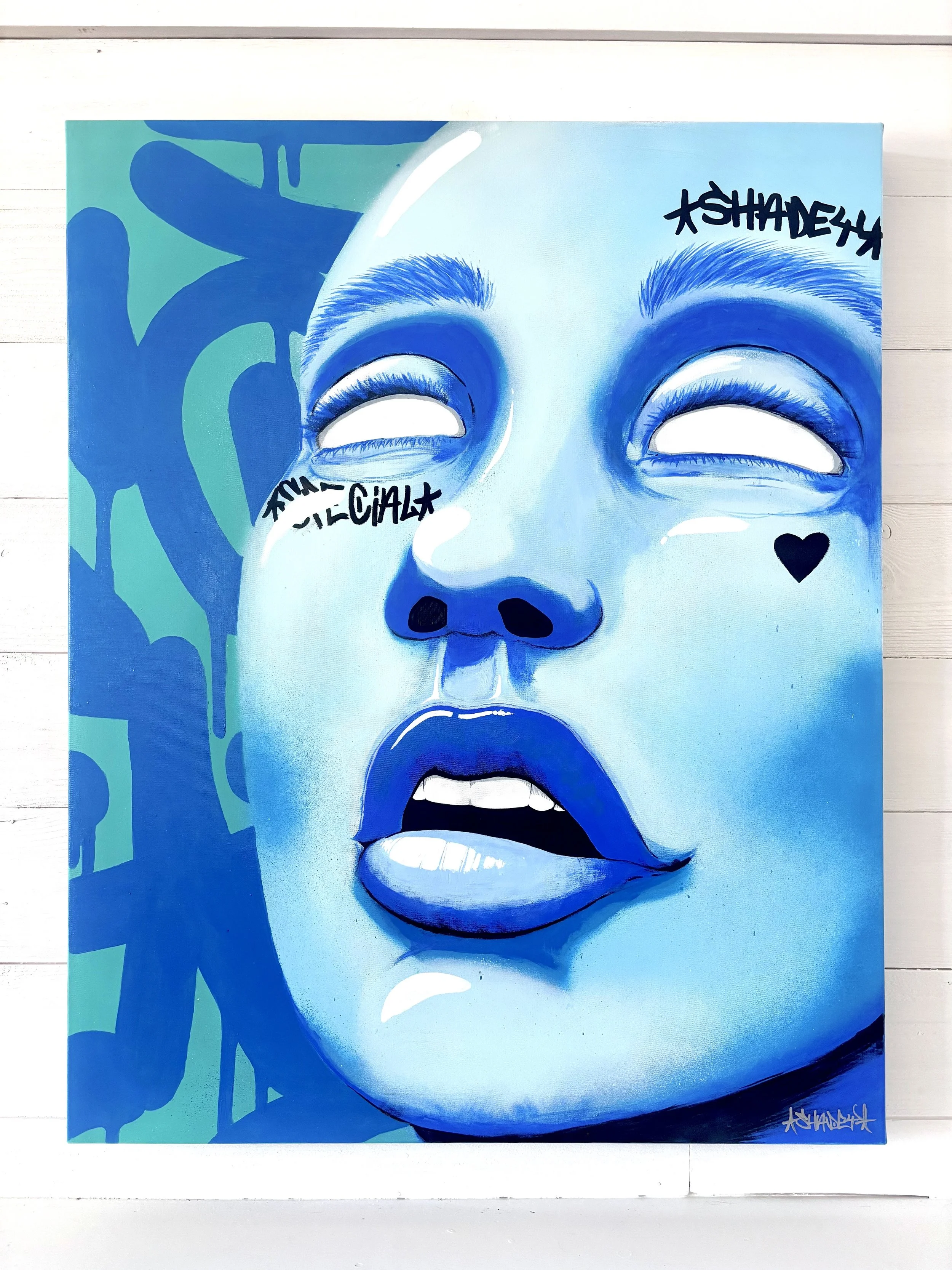 Blue-toned portrait of a woman's face with her eyes closed, lips slightly parted, and expressive eyebrows. Graffiti-style signatures and a small heart are on her face, against a blue and green abstract background.