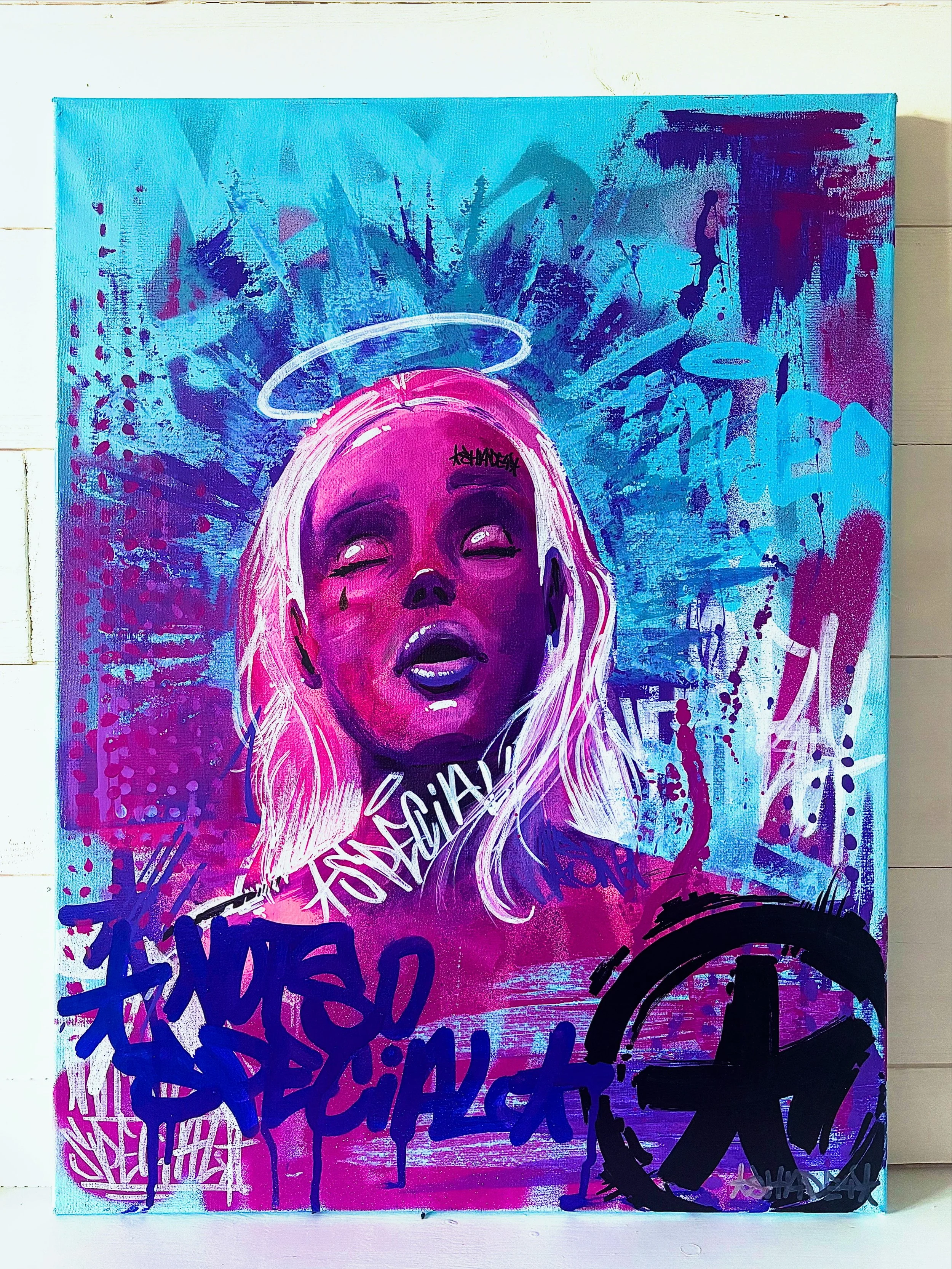 Street art portrait of a woman with blonde hair, closed eyes, a tear, and a halo, with vibrant blue, purple, and pink spray paint background and graffiti tags.