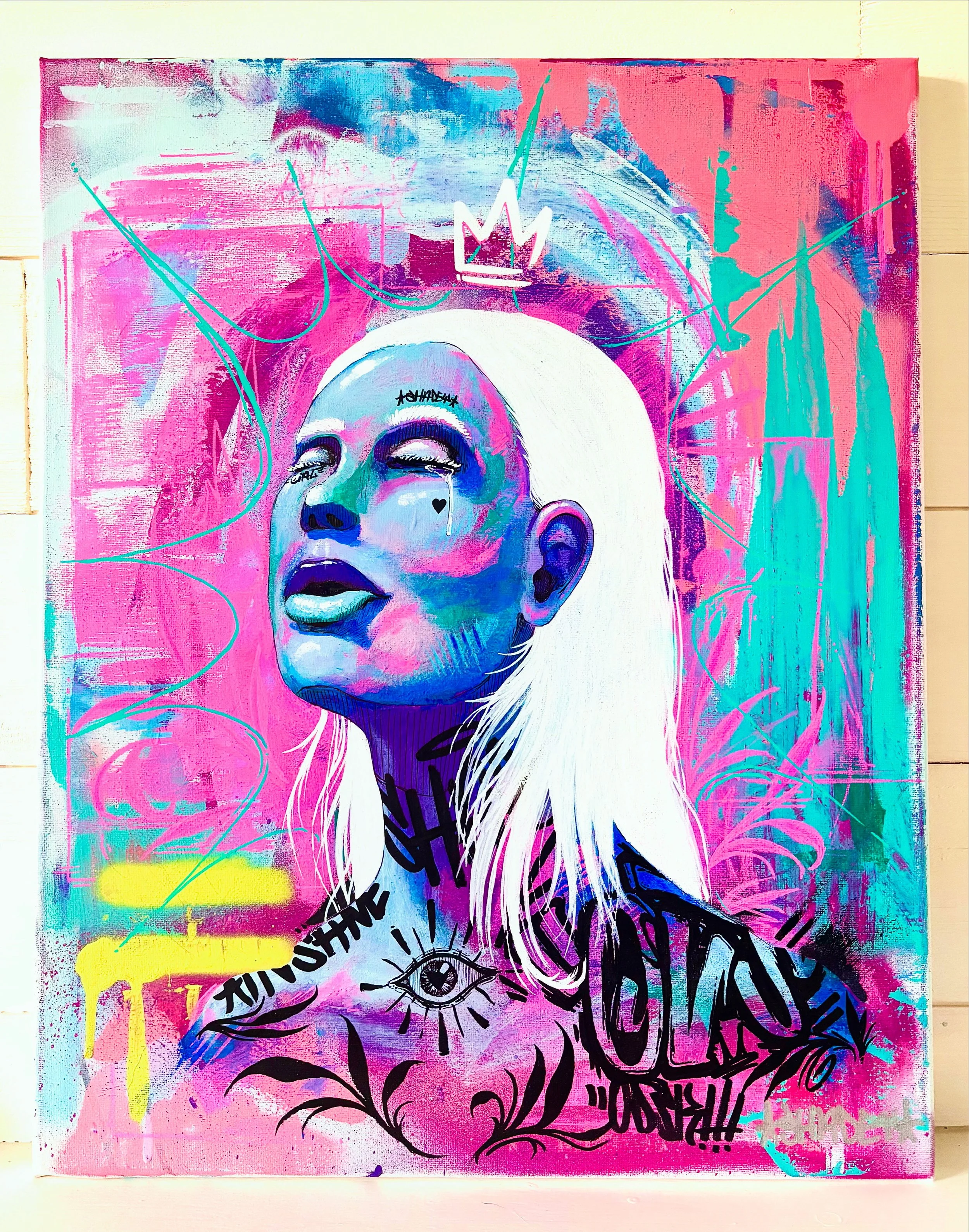 Colorful graffiti art of a woman with white hair, closed eyes, and tongue out, set against a pink, blue, and teal background with various symbols, including a crown, an eye, and graffiti text.