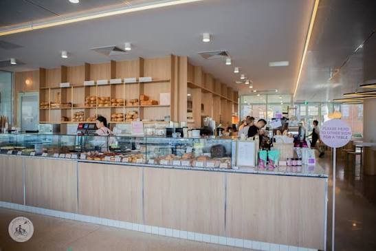 A modern bakery counter with various baked goods on display in a well-lit cafe.