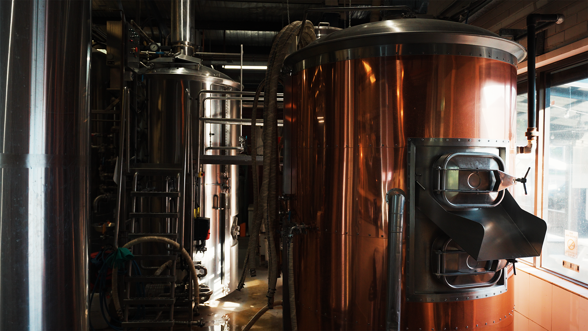 Copper fermentation and brewing tanks in an industrial brewery space.