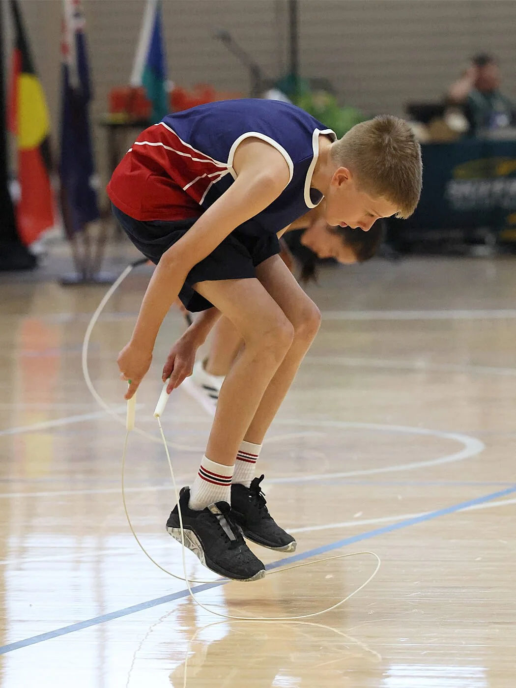 A boy jumping rope on a gymnasium floor during a jump rope competition.