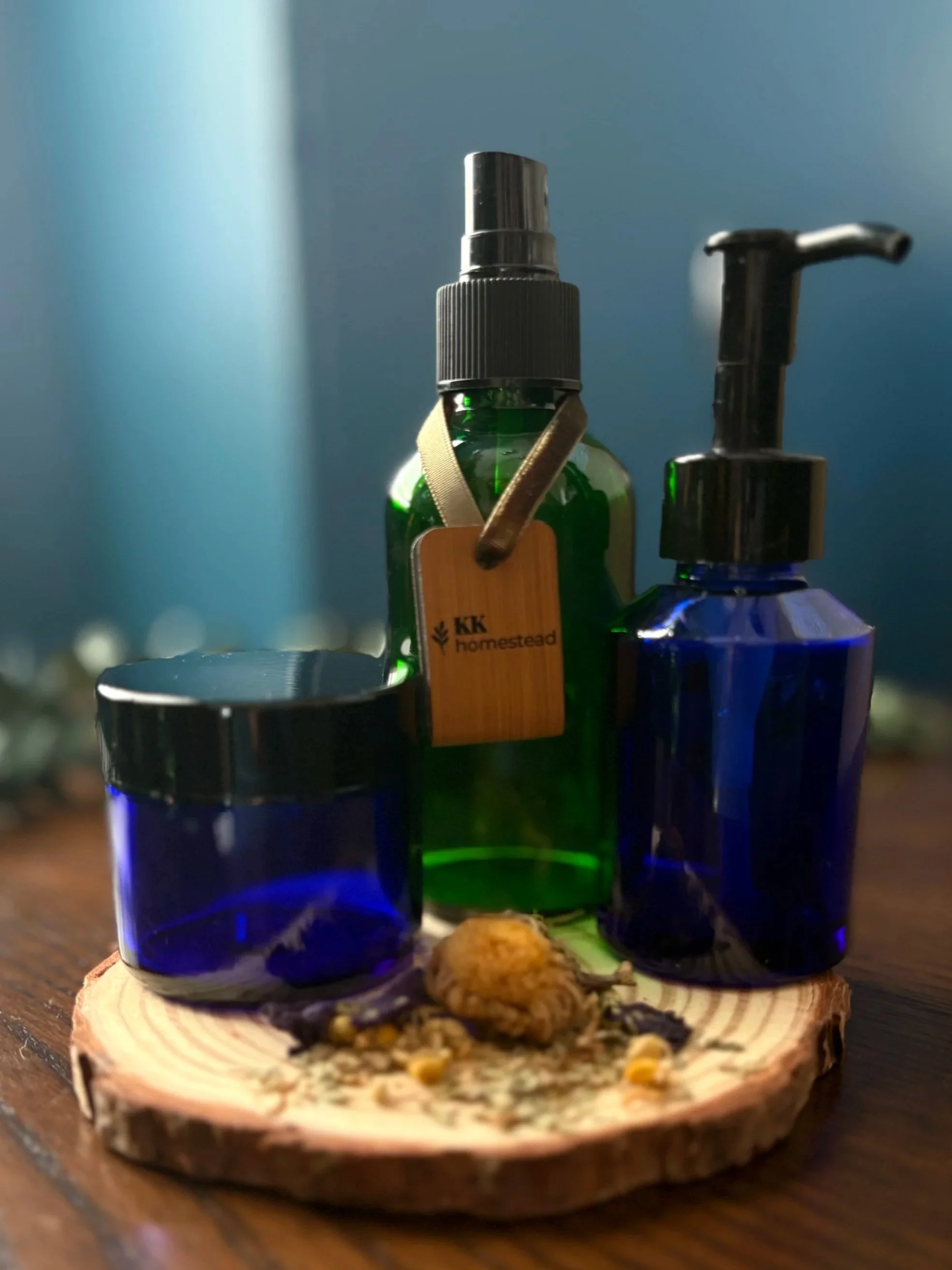Blue glass apothecary bottles and spray bottle on wooden slice