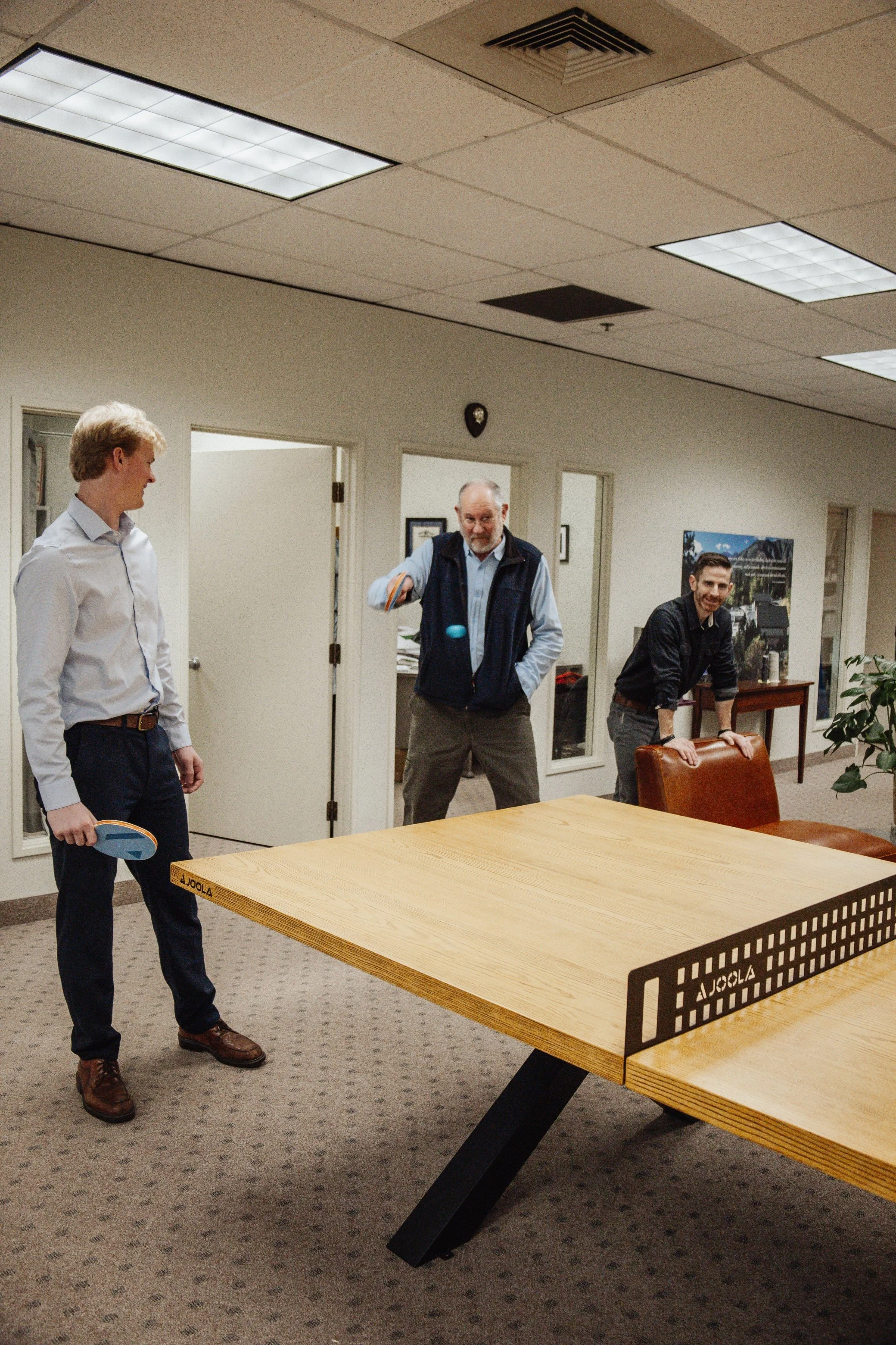 Employees playing ping pong together in shared space