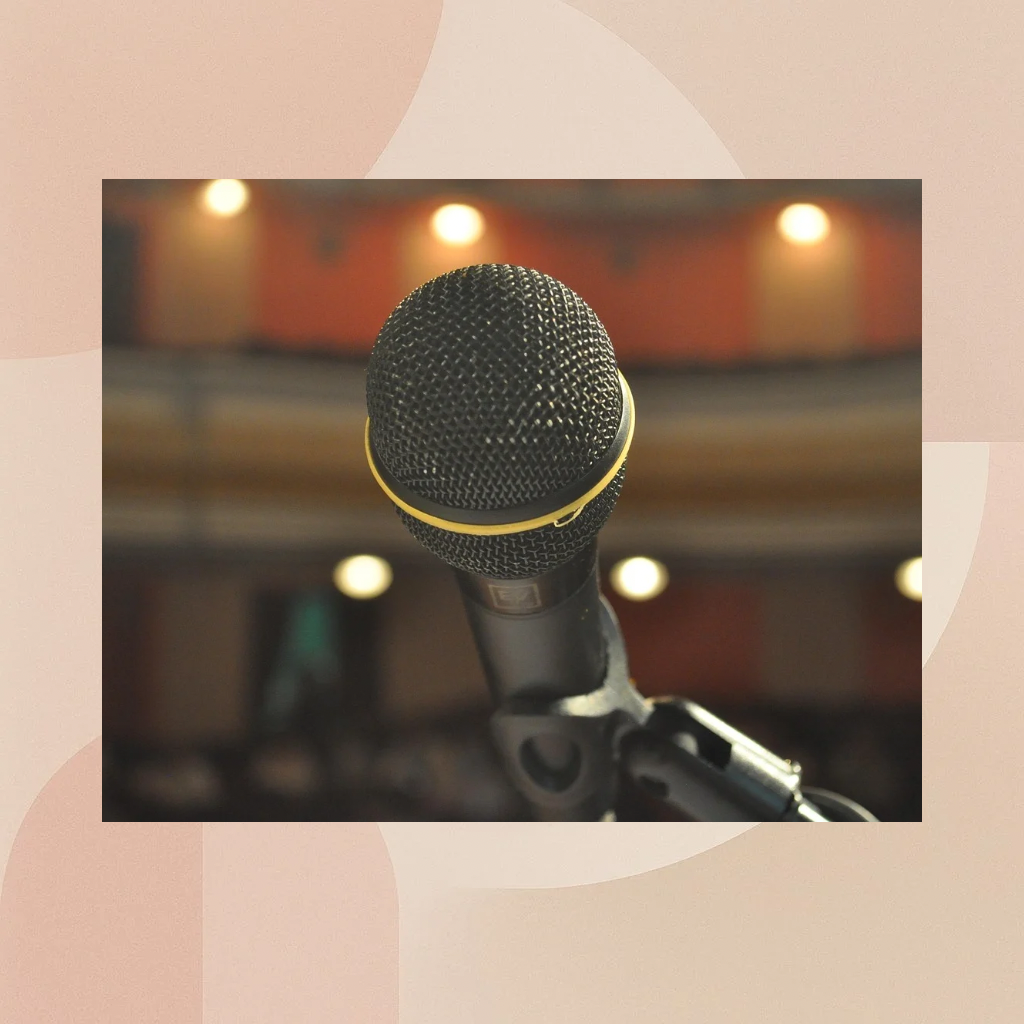 Close-up of a microphone on a stage with blurred lights in the background.