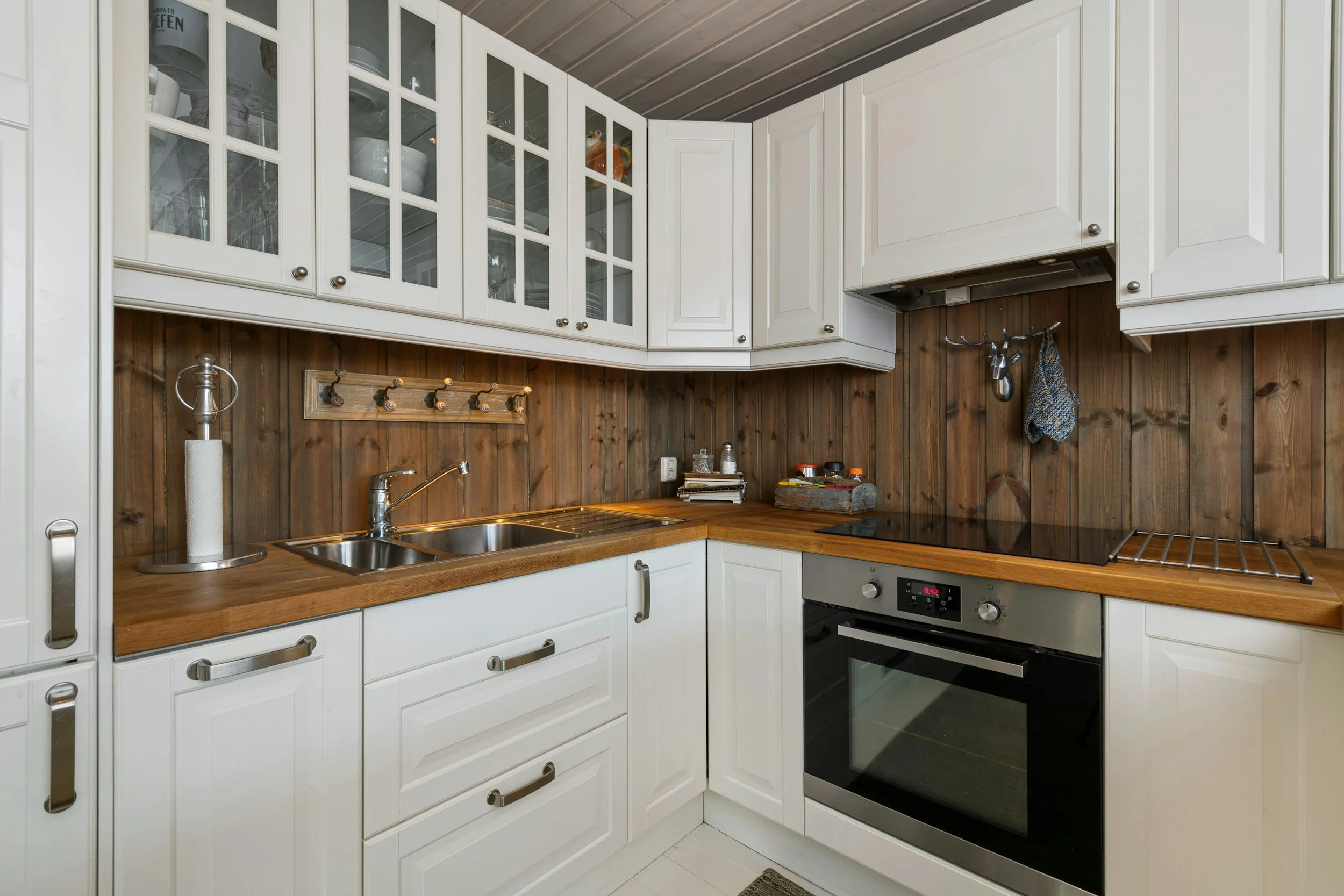 Farmhouse style L-shaped kitchen with white cabinets and natural wood countertops
