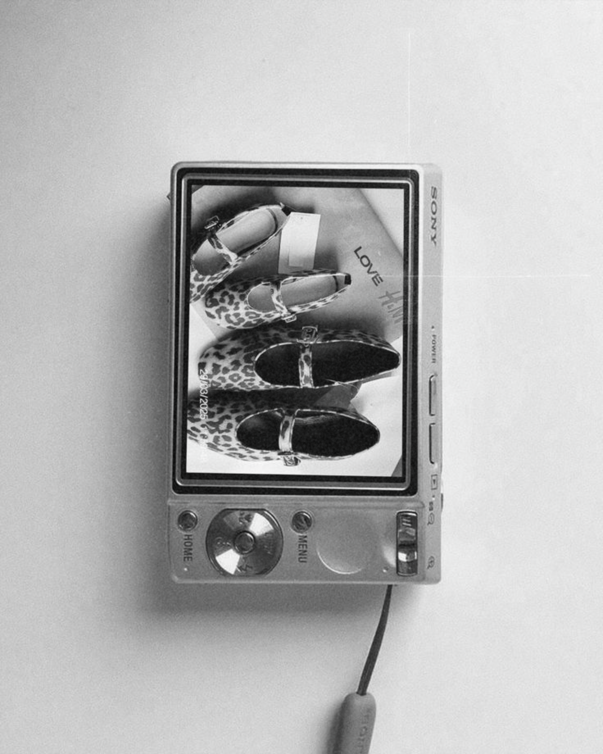 A digital camera displaying an image of three pairs of leopard print shoes and a love note on the screen.