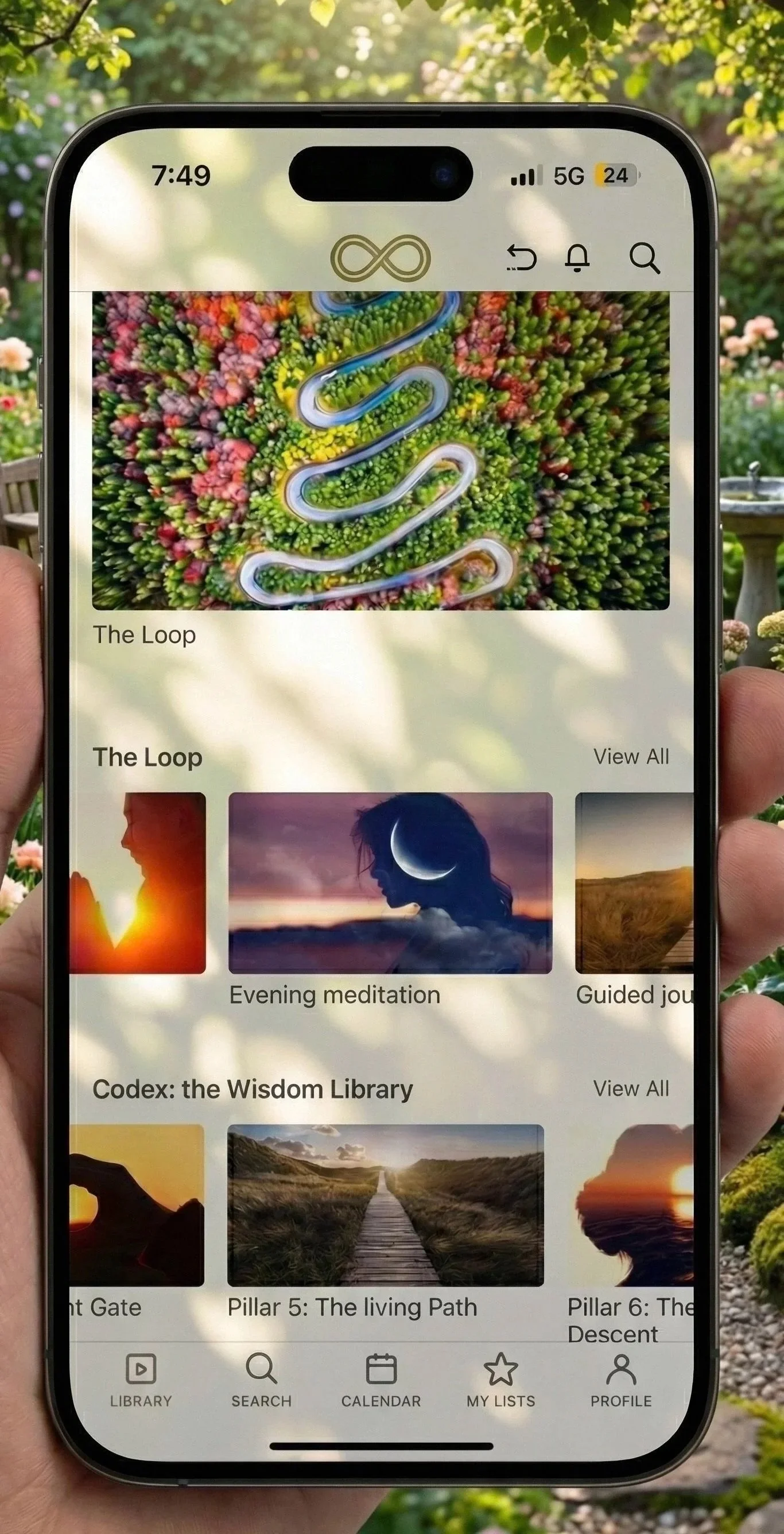 A smartphone displaying an app with various spiritual and meditation content, including images of nature, moon, and sunset, set against a background of a garden with flowers.