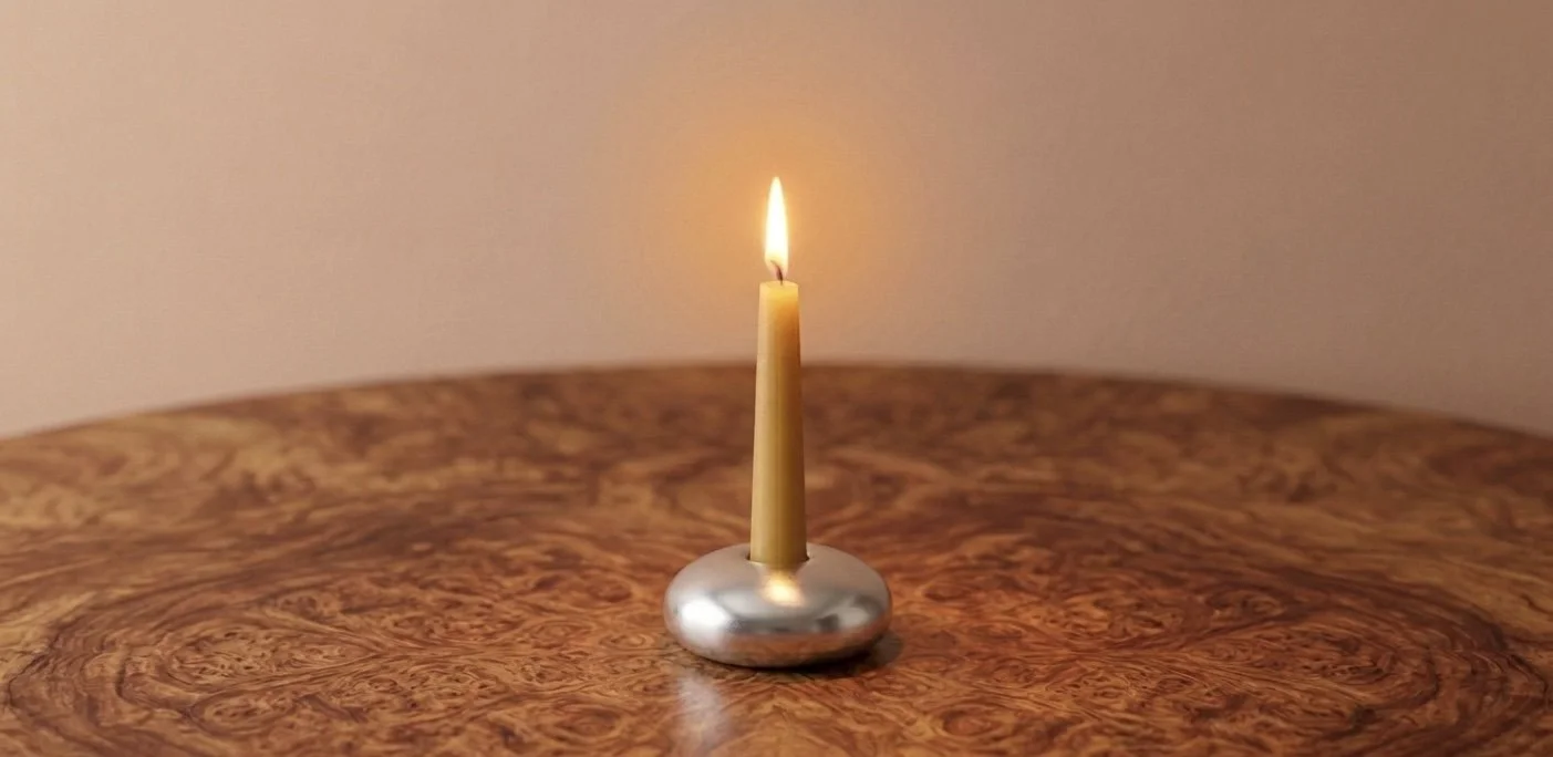 A lit meditation beeswax candle on a silver holder placed on a wooden surface. Meditation candle for a guided 20 mins meditation.