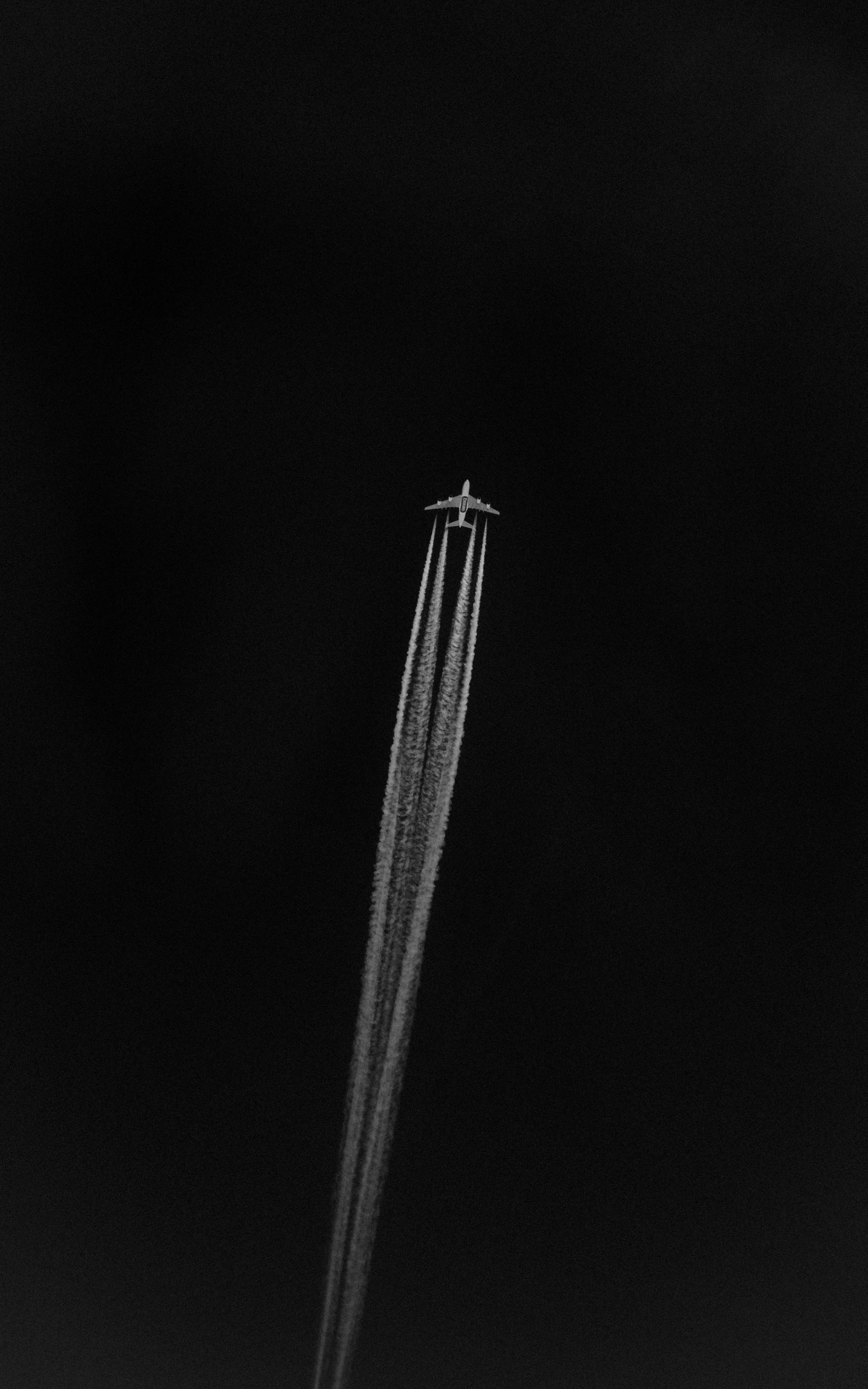 An airplane flying high in the sky leaving contrail behind it.