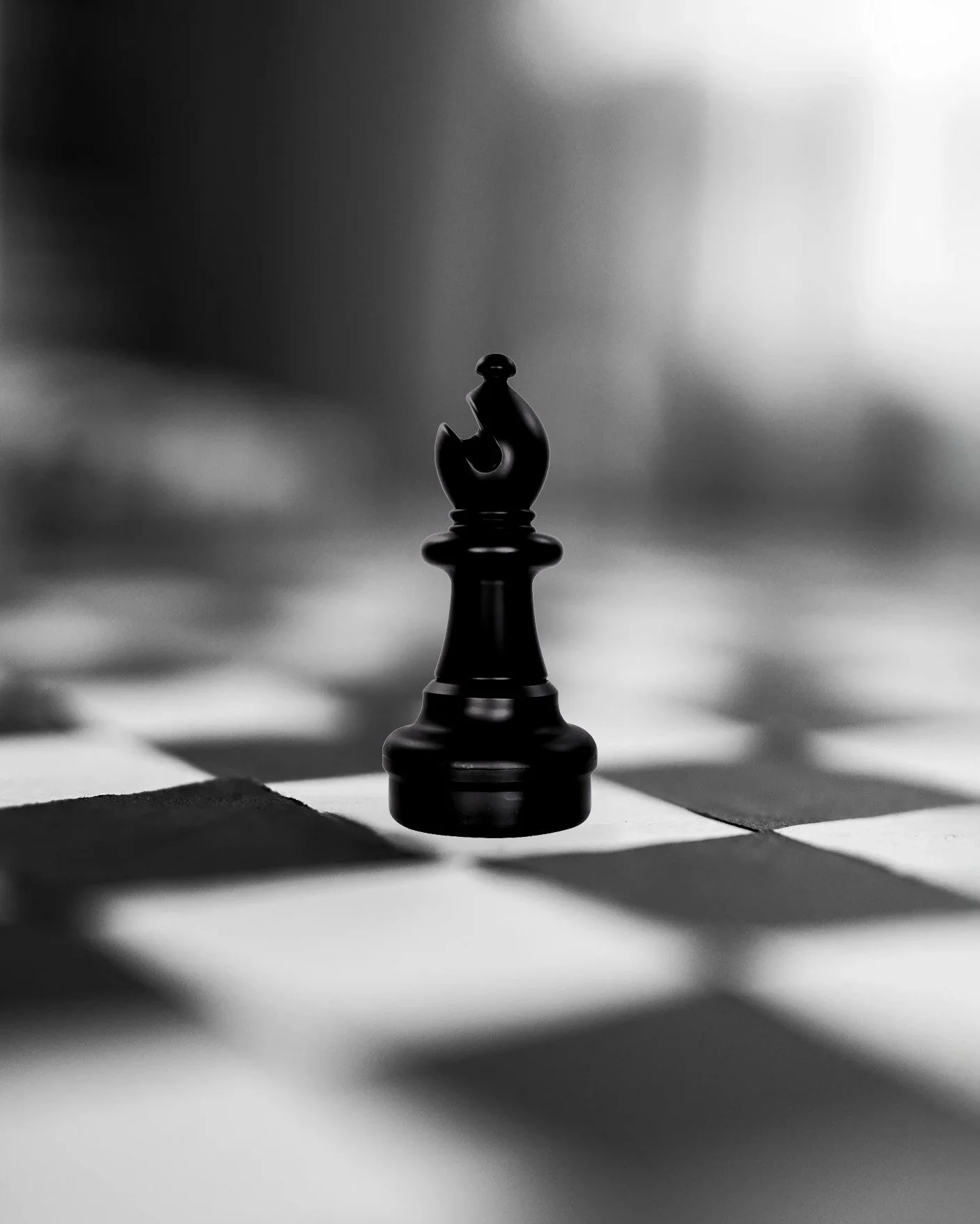 A black chess king piece stands on a chessboard in black and white, with light and shadow creating a dramatic effect.