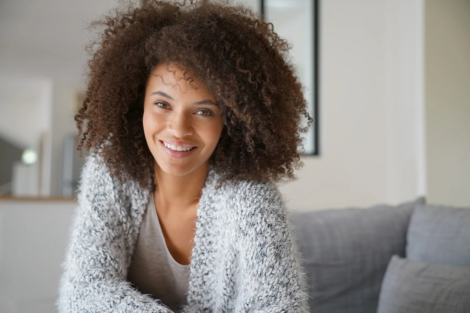Smiling woman with natural curly hair and soft texture, conveying warmth, confidence, and an effortless, lived-in look.