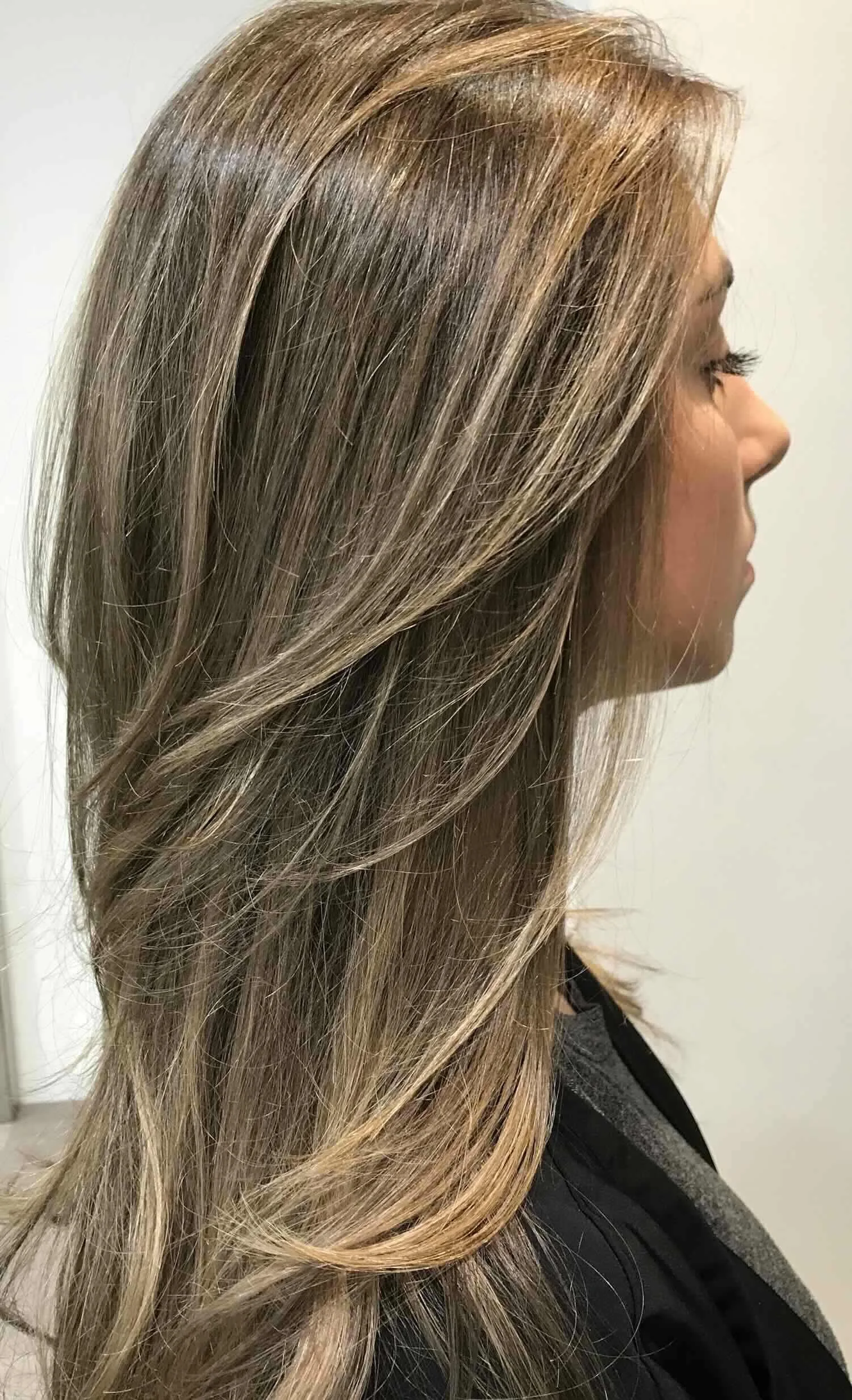 Soft balayage with lived-in dimension on long brunette hair, featuring warm beige highlights and natural movement.