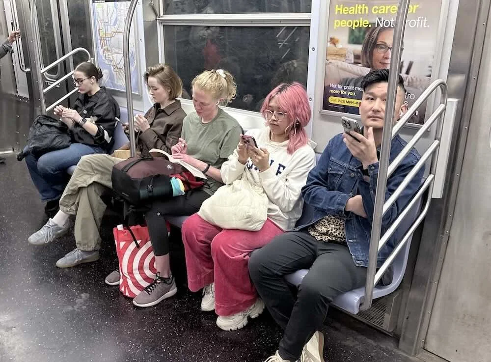 Group of subway riders on the A train, woman with vivid pink hair at center, New York City
