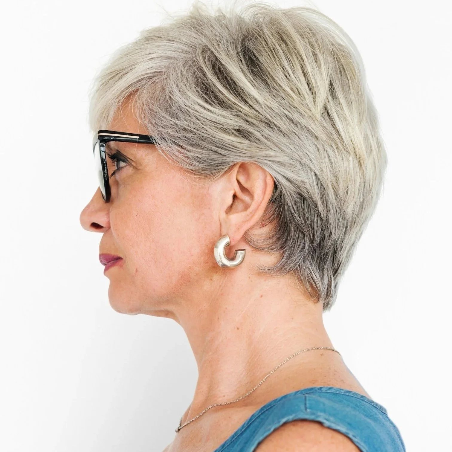 Side profile of a woman with naturally blended short gray hair, showing soft texture and an even, refined finish.