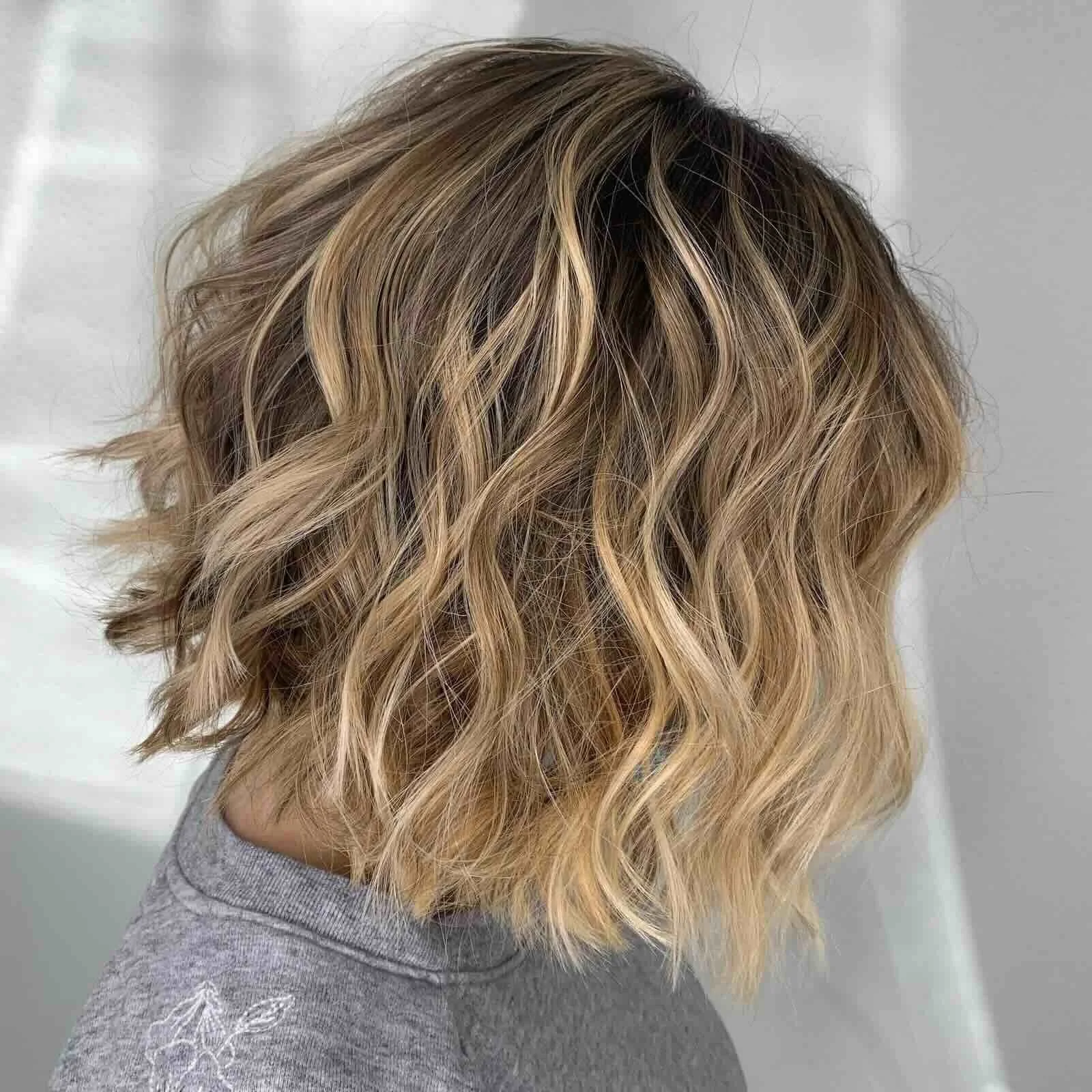 Side view of textured blonde balayage with soft waves, natural root depth, and lived-in dimension designed for effortless grow-out.