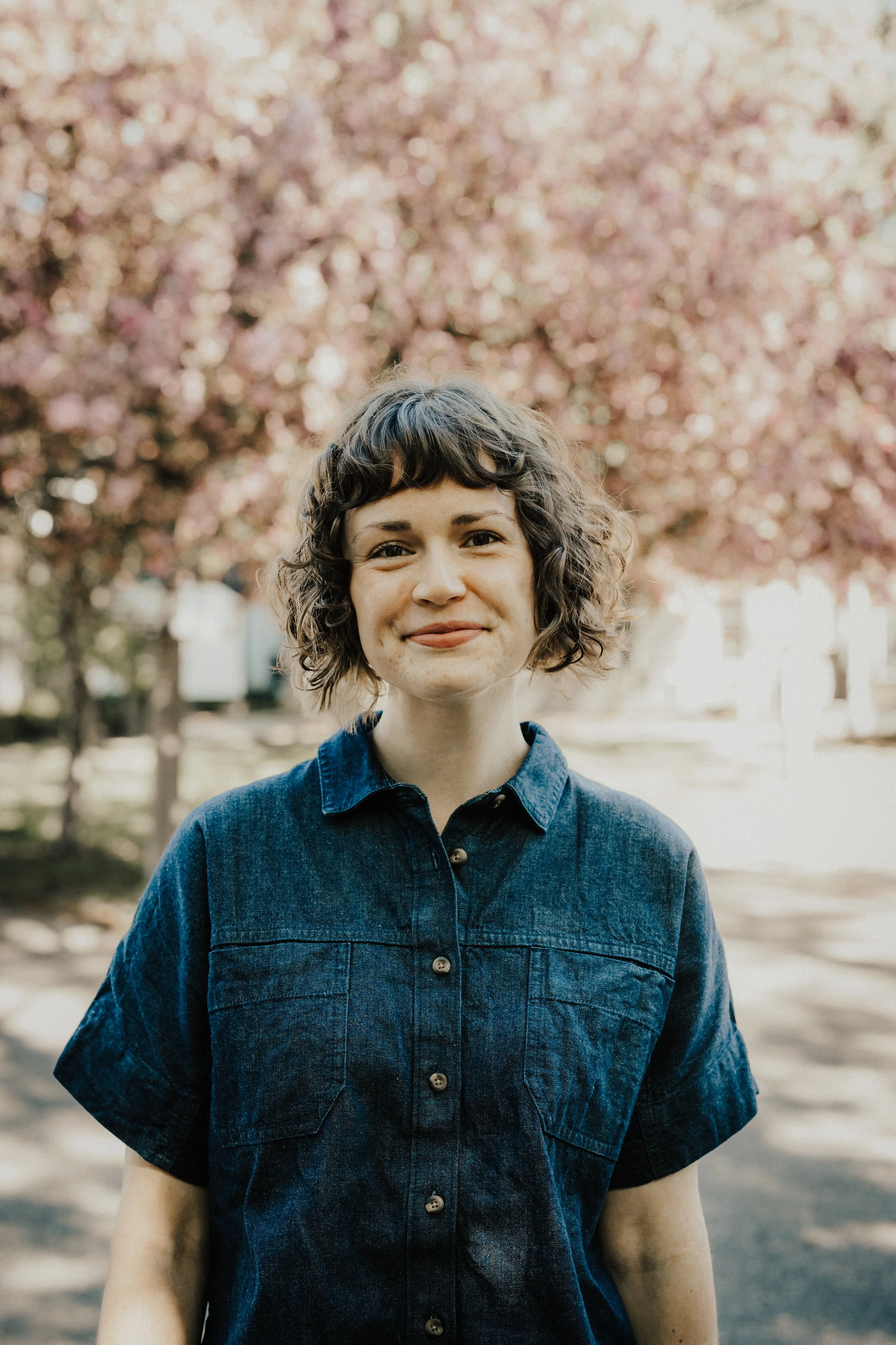 Liz Campbell, individual, couples, & family therapist at Resourced & Resilient, standing in a plant-filled therapy space. Click here for Liz Campbell's bio.