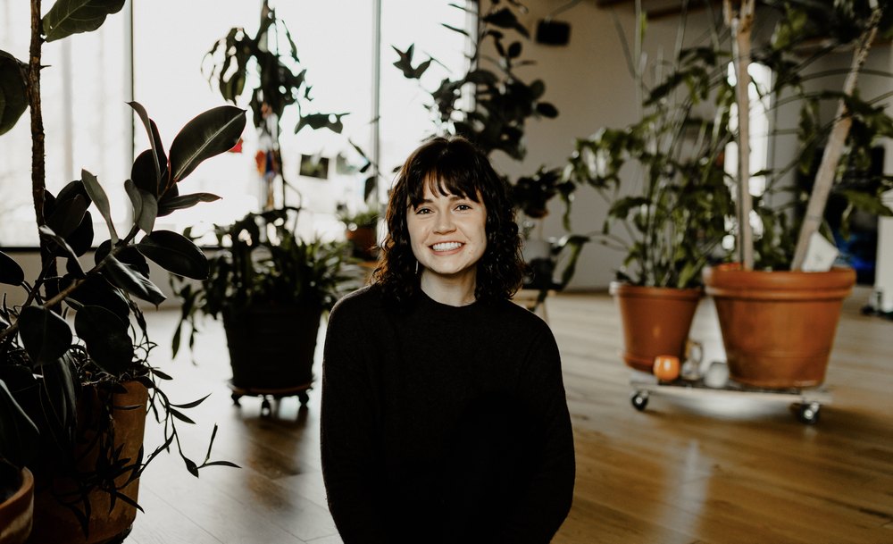 Liz Campbell, individual, couples, & family therapist at Resourced & Resilient, standing in a plant-filled therapy space. Click here for Liz Campbell's bio.