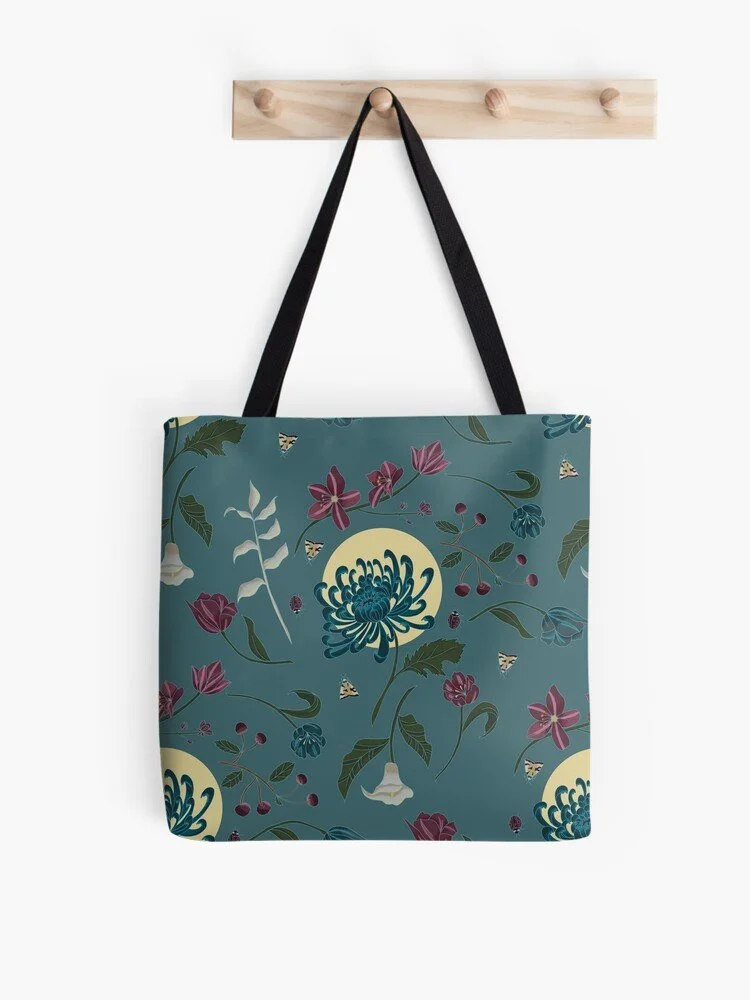 A tote bag with a floral pattern hanging from a wooden wall hook against a white background.