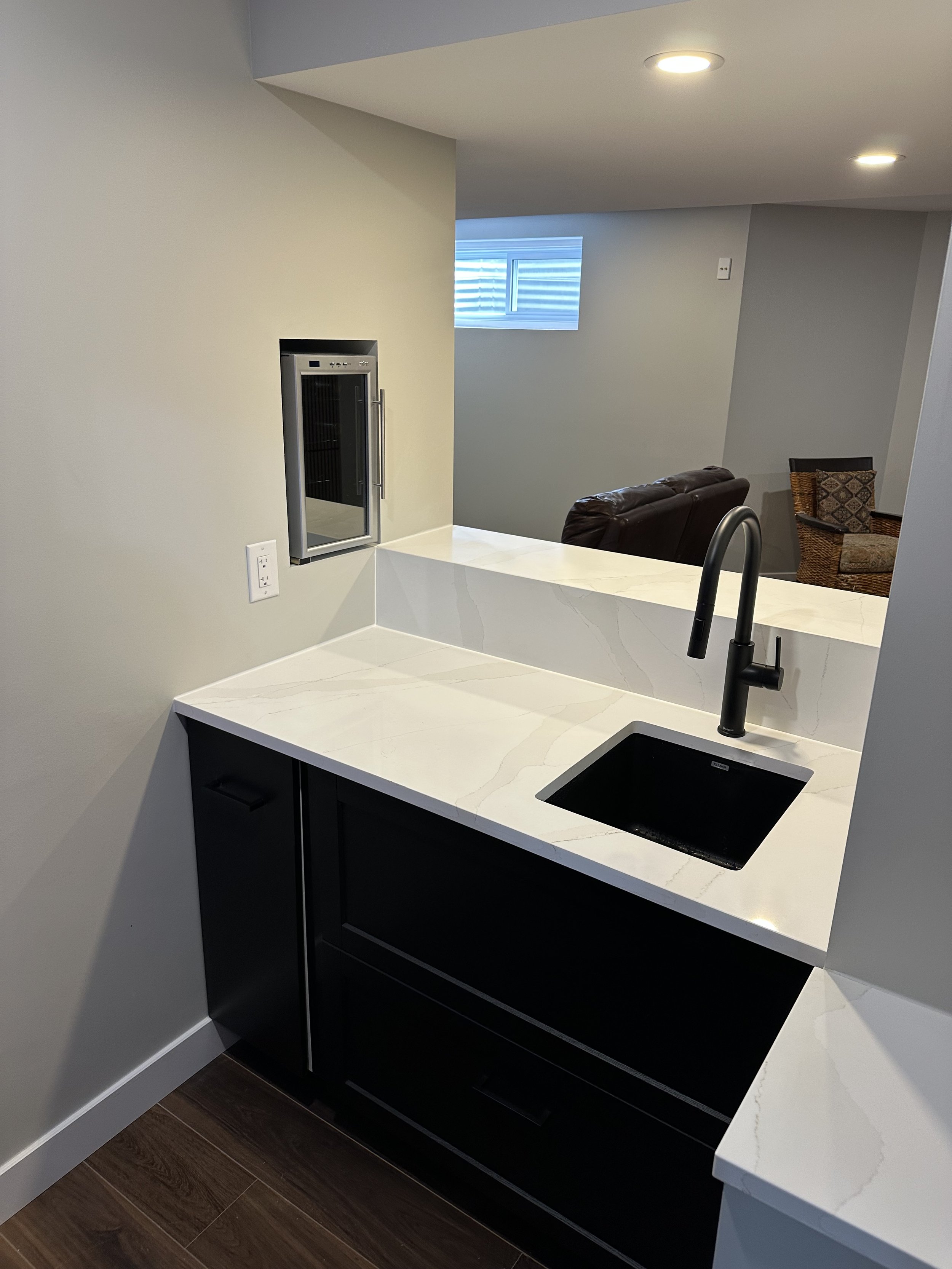 A living room with a modern wooden slat wall, a horizontal electric fireplace, a table with a large silver lamp, a cup, and a remote control, and a flat-screen TV mounted above the fireplace.