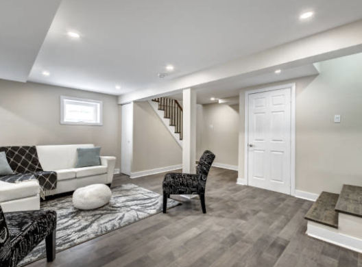 Living room with white sofa, black chairs, and a gray area rug, with stairs in the background.