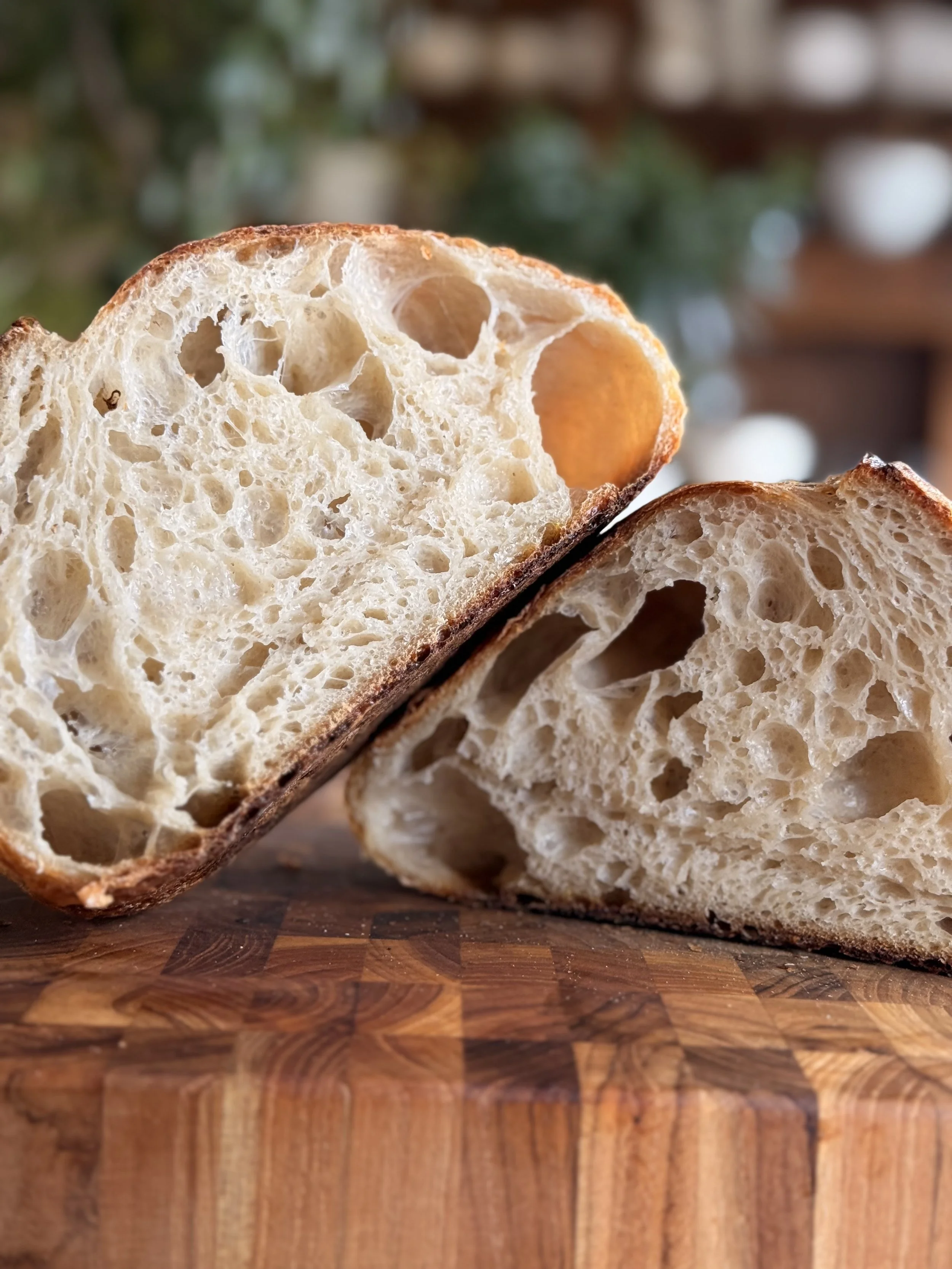 Close-up view of a sliced loaf of artisan bread on a wooden cutting board with a blurred background.