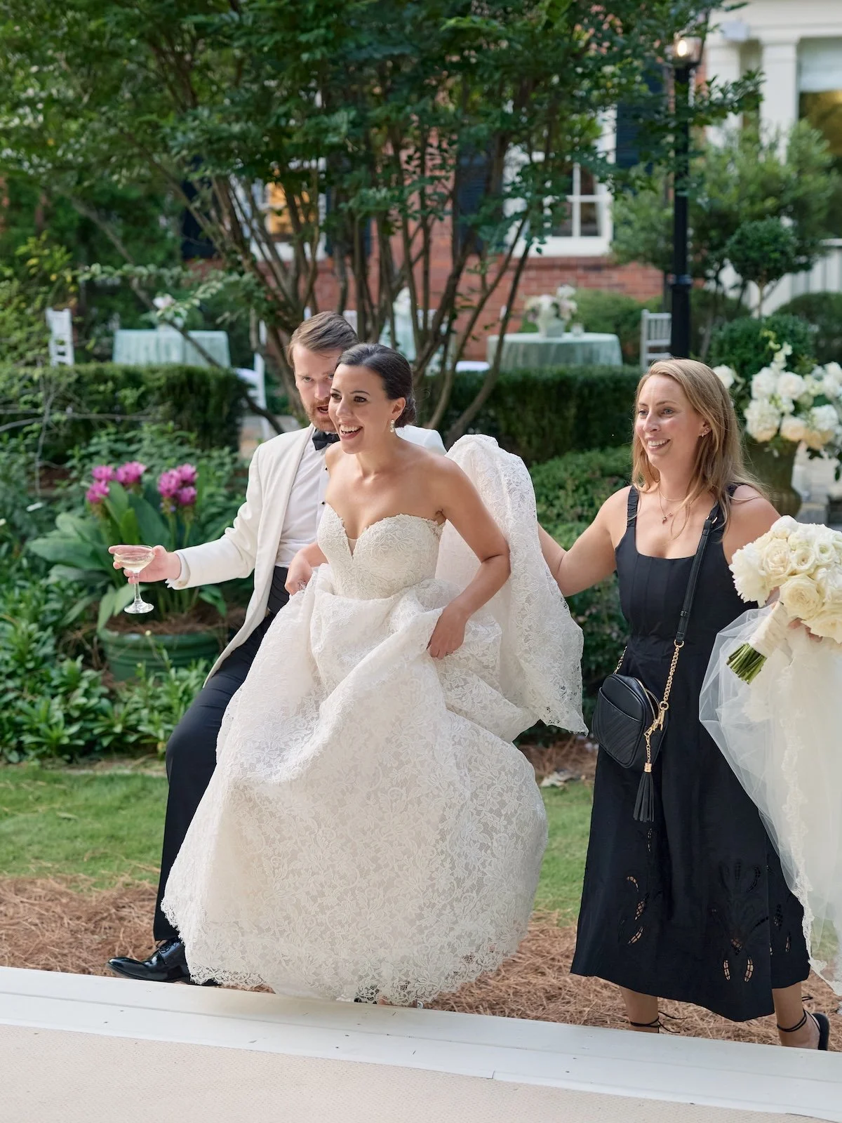 Luxury wedding planner adjusting the bride's veil as the newlyweds explore their reception reveal