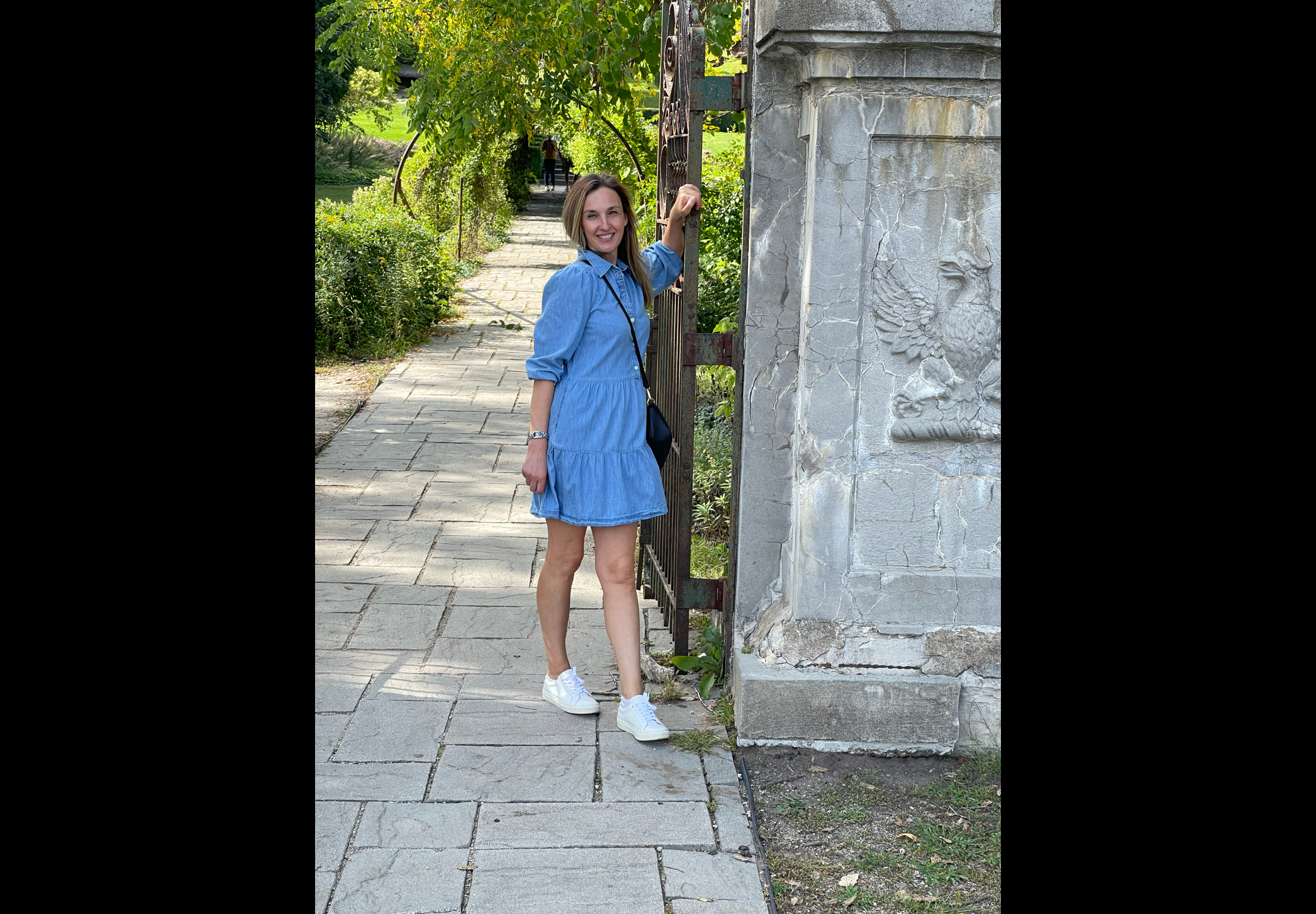 Professional esthetician in Wheaton IL standing outdoors in a natural garden setting smiling and welcoming representing a trusted facial studio focused on personalized skincare and client care