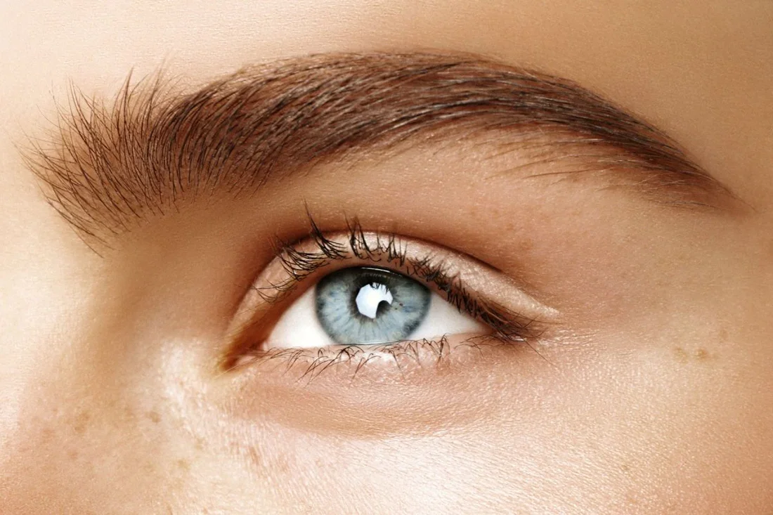Professional esthetician performing eyebrow waxing and precise brow design to shape and define natural brows.