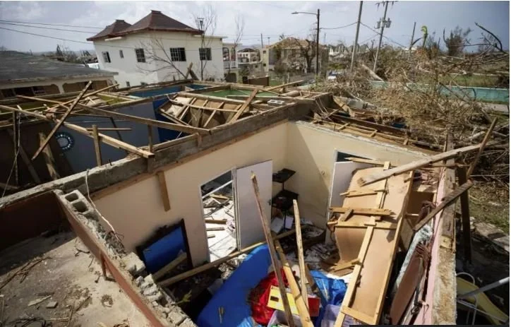 A house completely destroyed with fallen debris, broken walls, and scattered furniture after severe storm or hurricane.