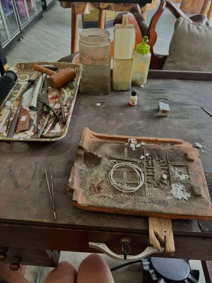 A worktable with assorted tools, metal wires, cleaning supplies, and a brick surface, in a workshop or craft space.