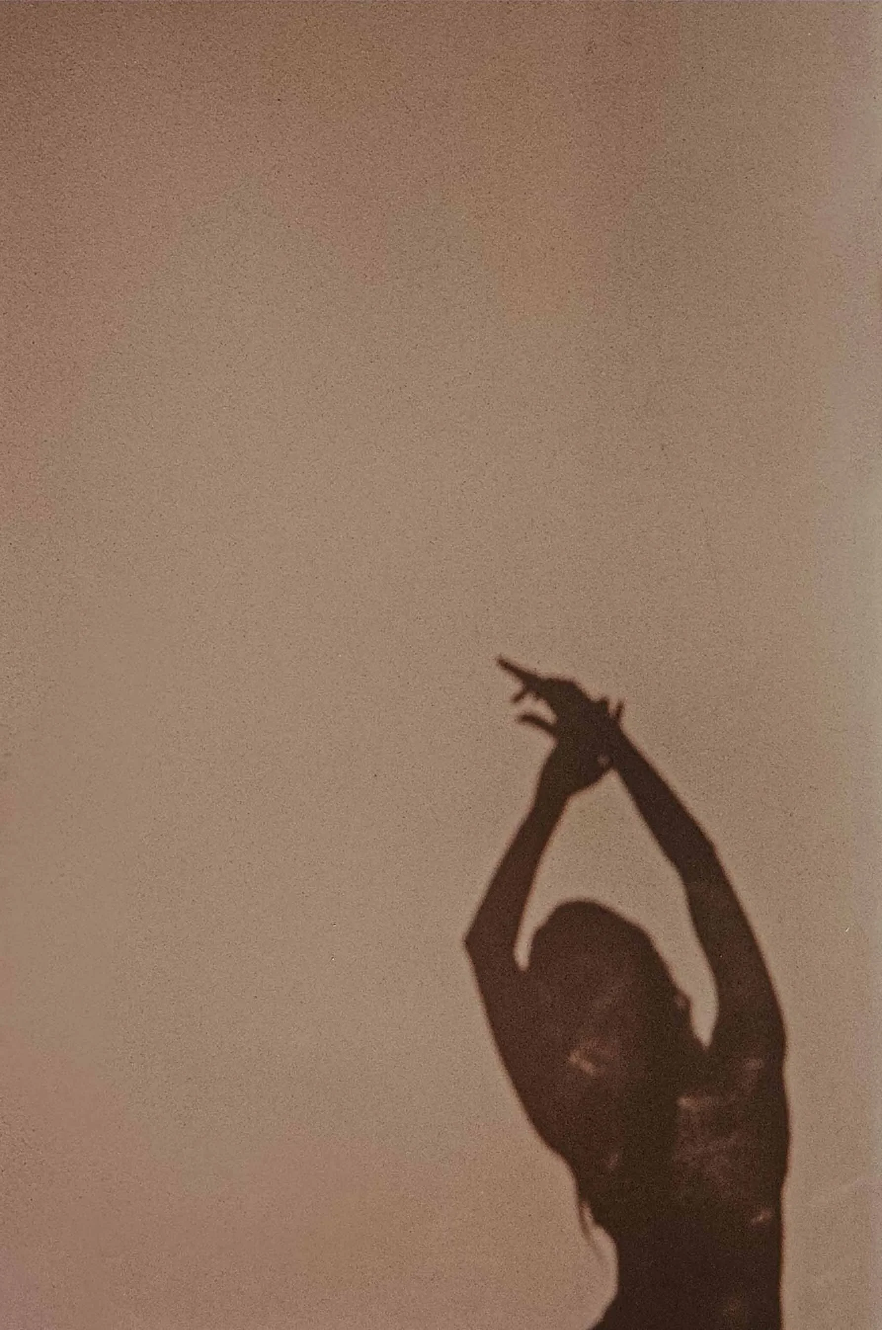 Silhouette of a person with arms raised above their head, making a gesture with their fingers against a plain background.