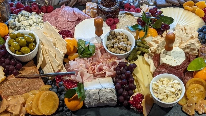 Assorted cheese and charcuterie spread with fruits, nuts, olives, and crackers.