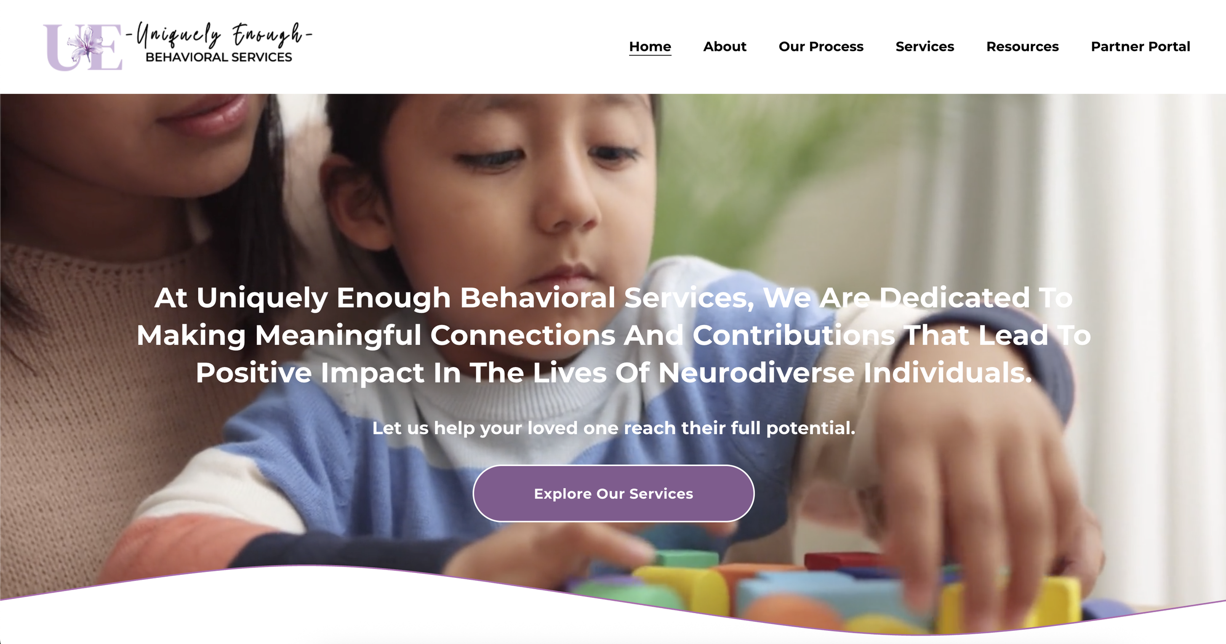 Homepage of Uniquely Enough Behavioral Services featuring a close-up of a woman and a young child engaged in an educational activity with colorful blocks, with navigation menu at the top and a greeting message overlay.