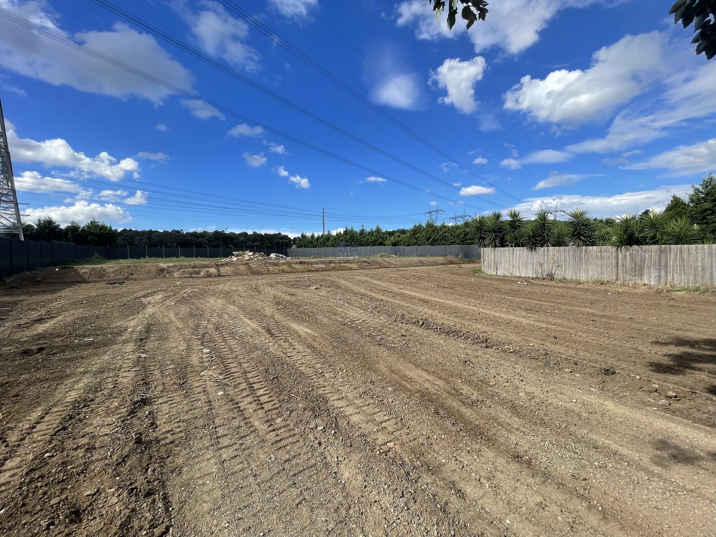 A yellow excavator digging up soil against a blue sky background.