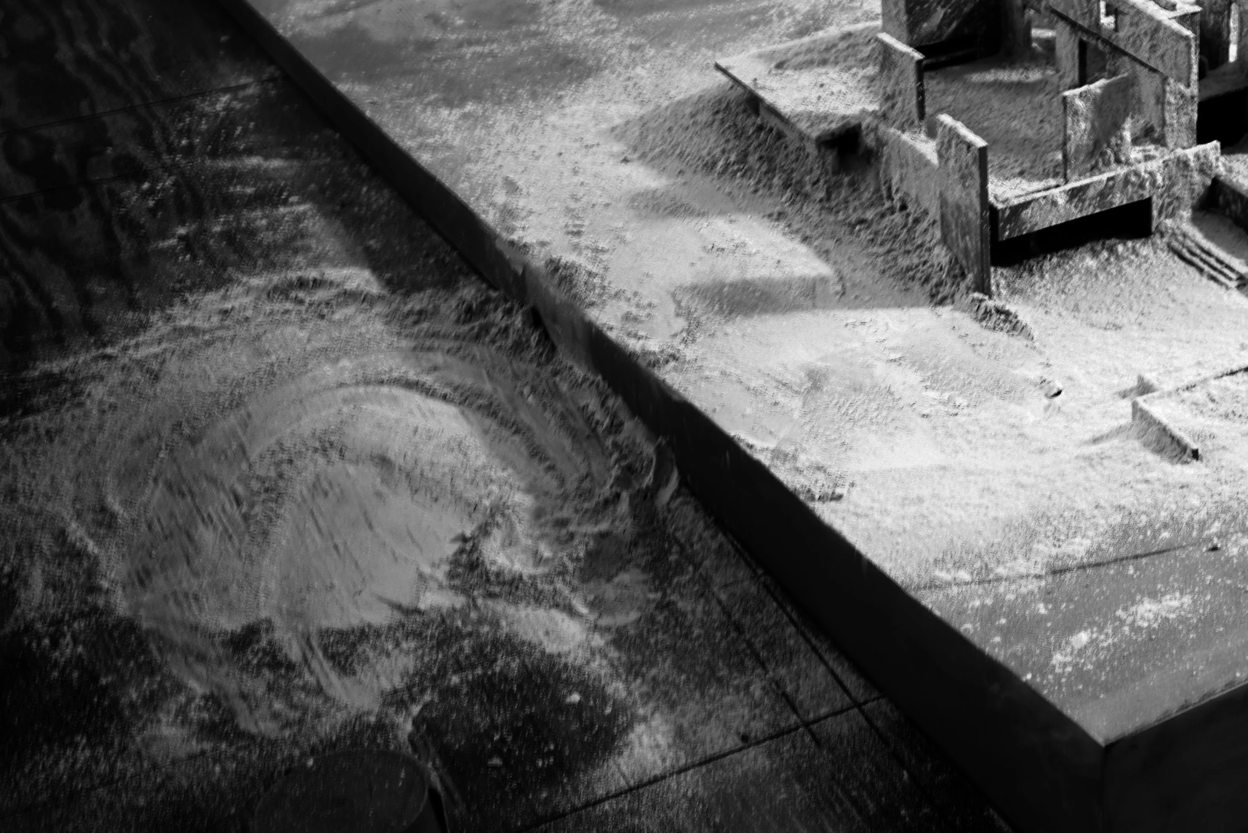 Model construction showing wooden formwork and concrete dust, on a wood workshop table.