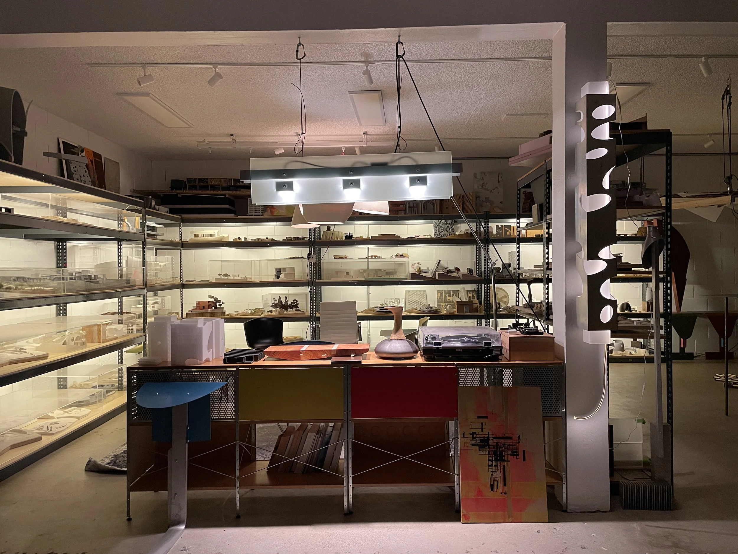 Display of framed artwork and decorative objects in a modern store with black metal shelving and bright lighting.