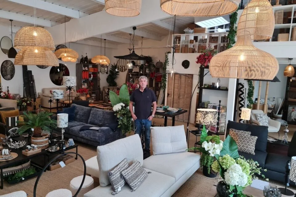 Une personne debout dans un magasin de décoration intérieure avec divers meubles et luminaires.