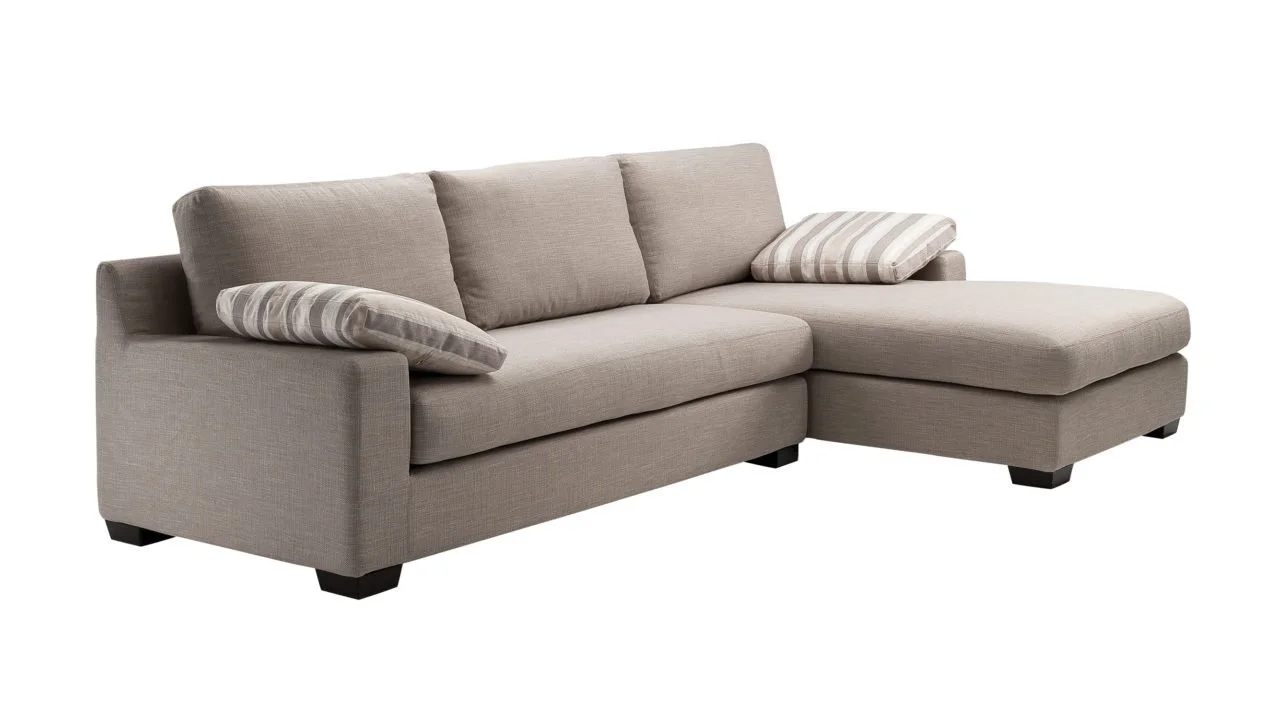 Un canapé d'angle beige avec deux coussins rayés