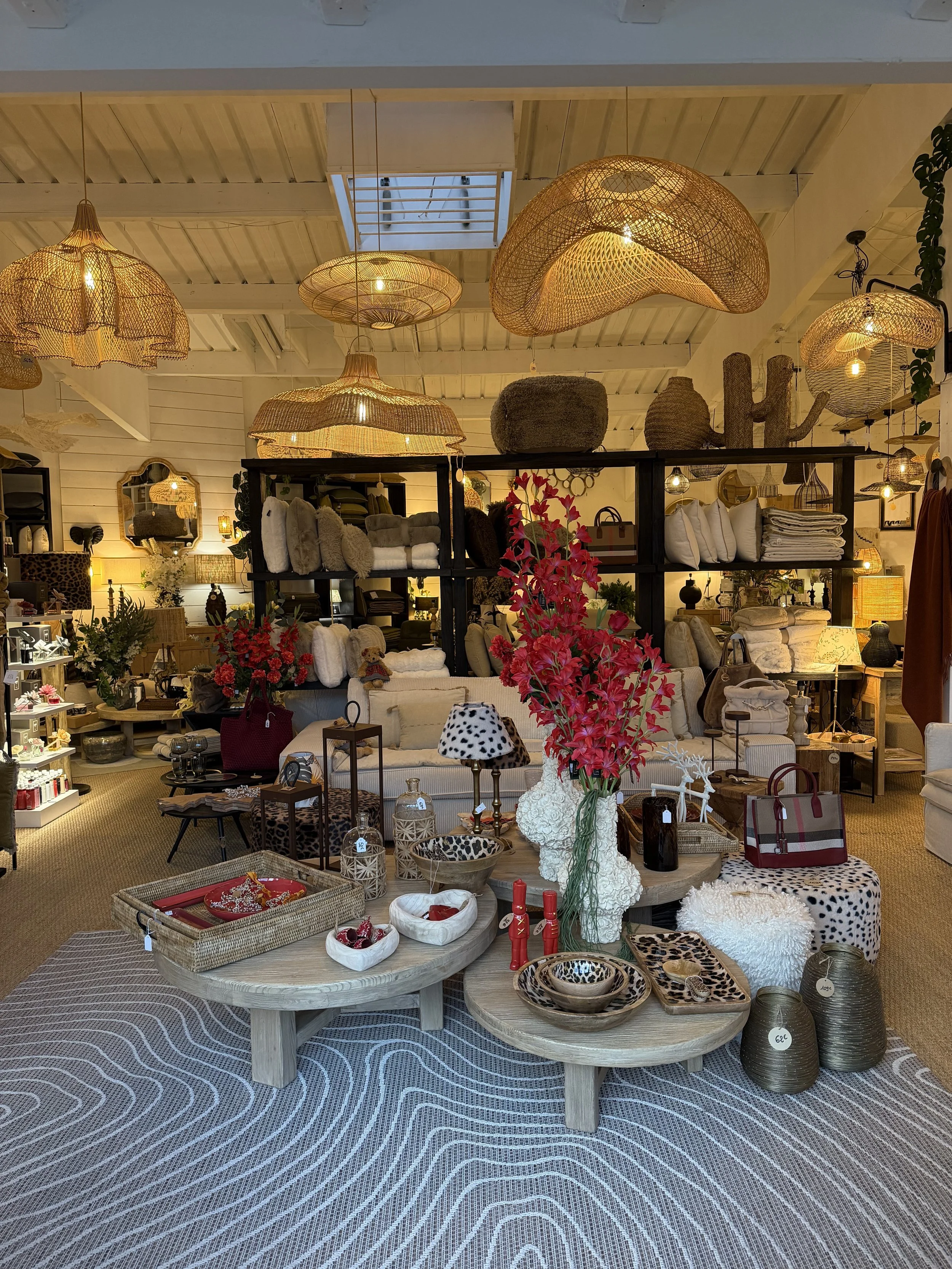 Intérieur d'une boutique de décoration avec des meubles, des accessoires et des luminaires en osier, des tapis, des vases et des objets décoratifs.