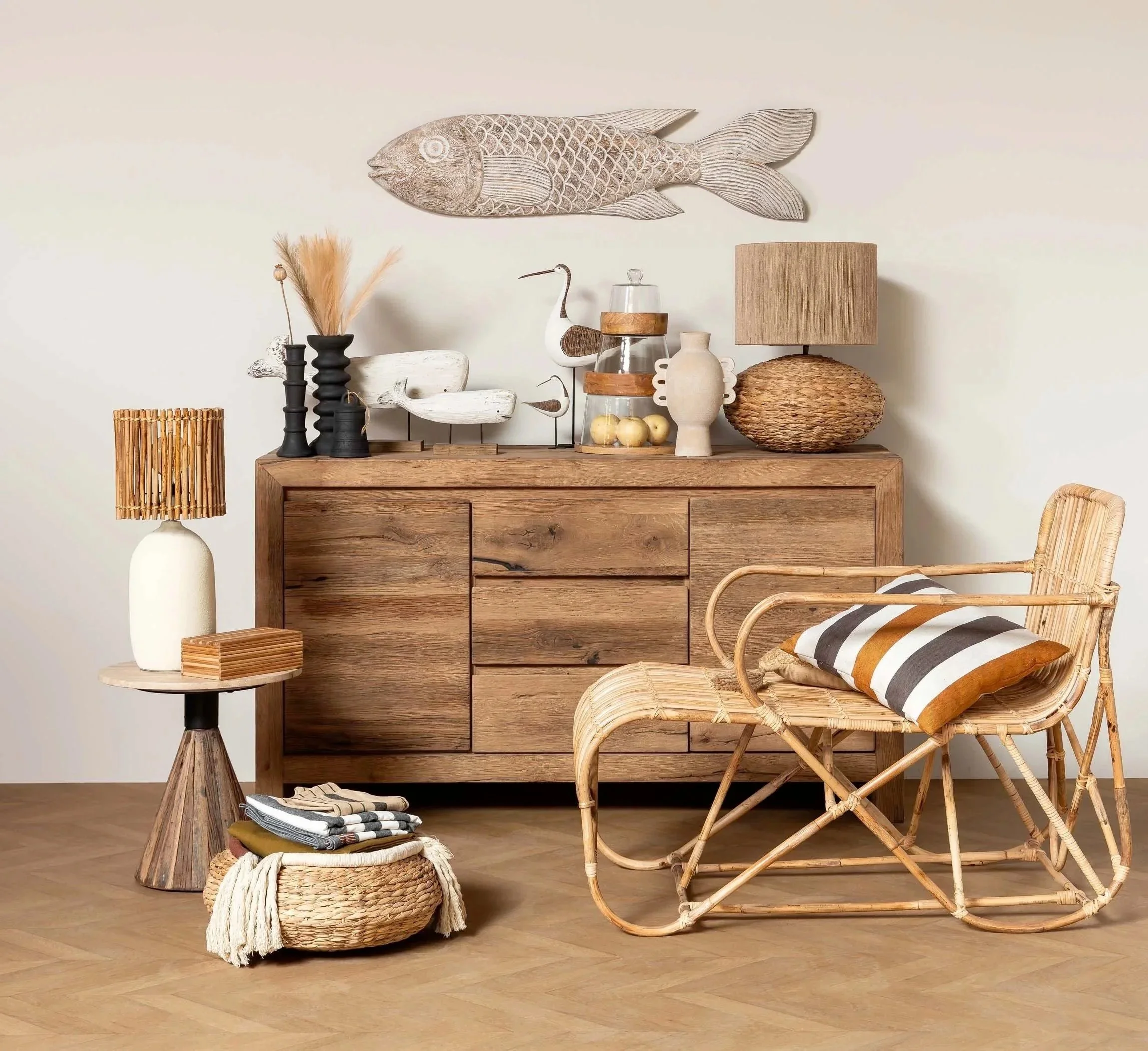 Intérieur avec meuble en bois, fauteuil en rotin, lampe, déco en céramique, verre, bois, et objets de décoration dans un style naturel et chaleureux.