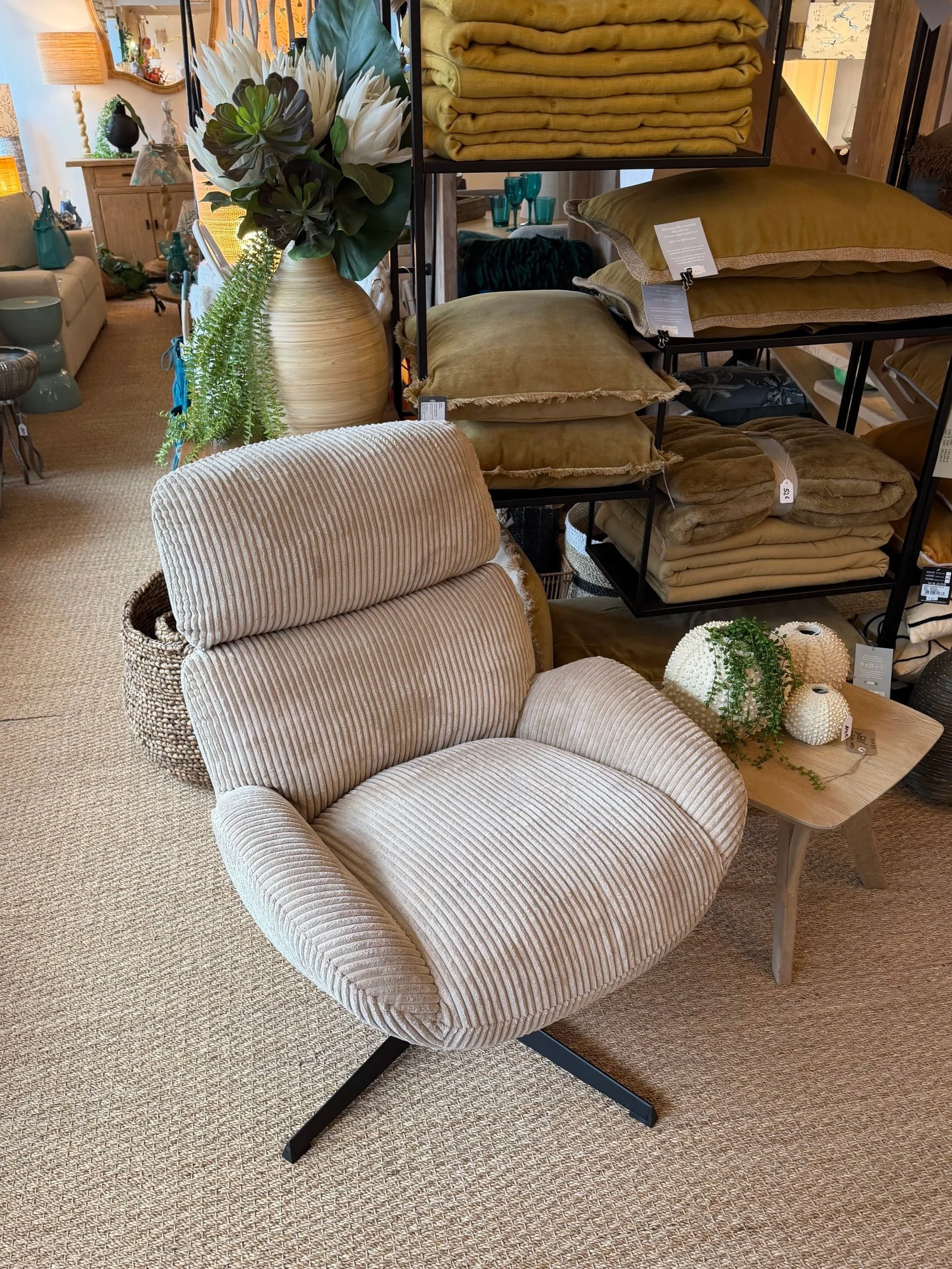 Fauteuil beige en tissu à motif côtelé dans un magasin de décoration intérieure.