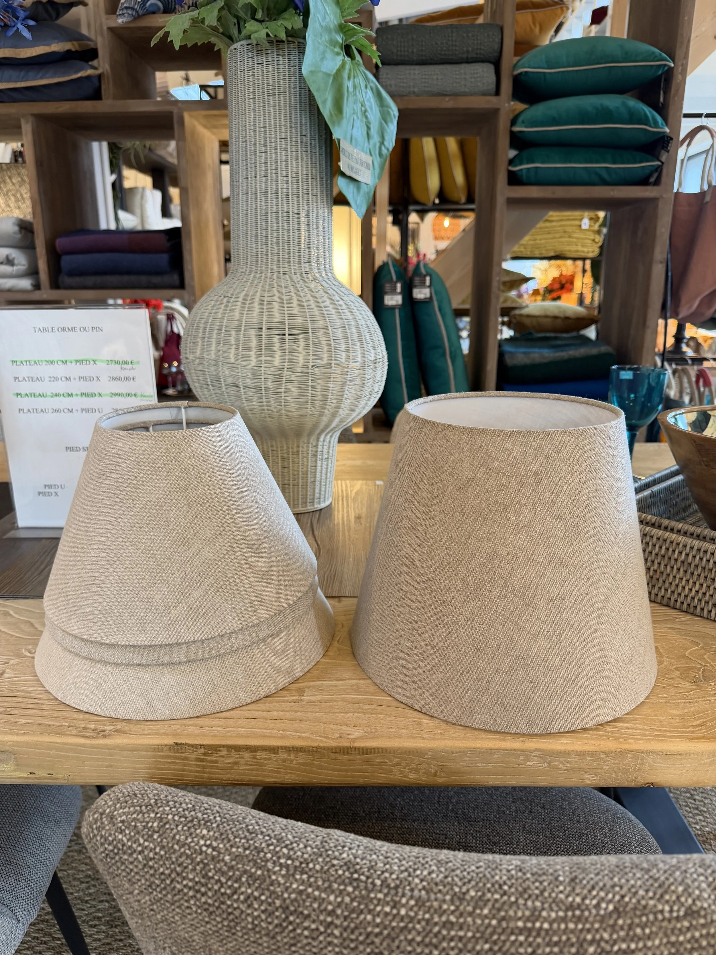 Deux abat-jours beige en tissu posés sur une table en bois.