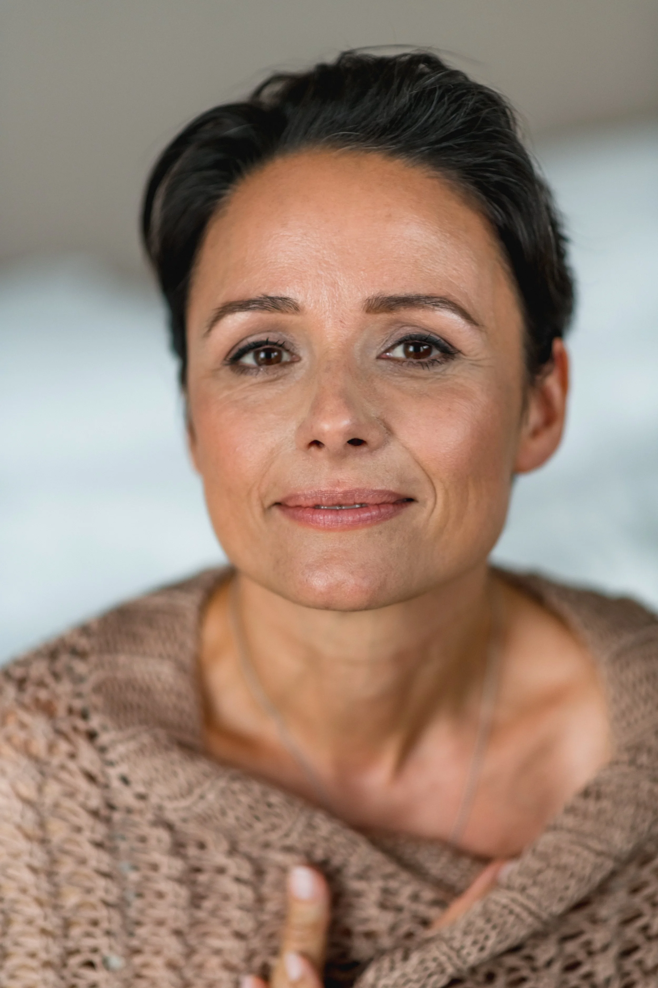 Nahaufnahme einer Frau mit kurzen schwarzen Haaren, die lächelt, im Hintergrund unscharf.