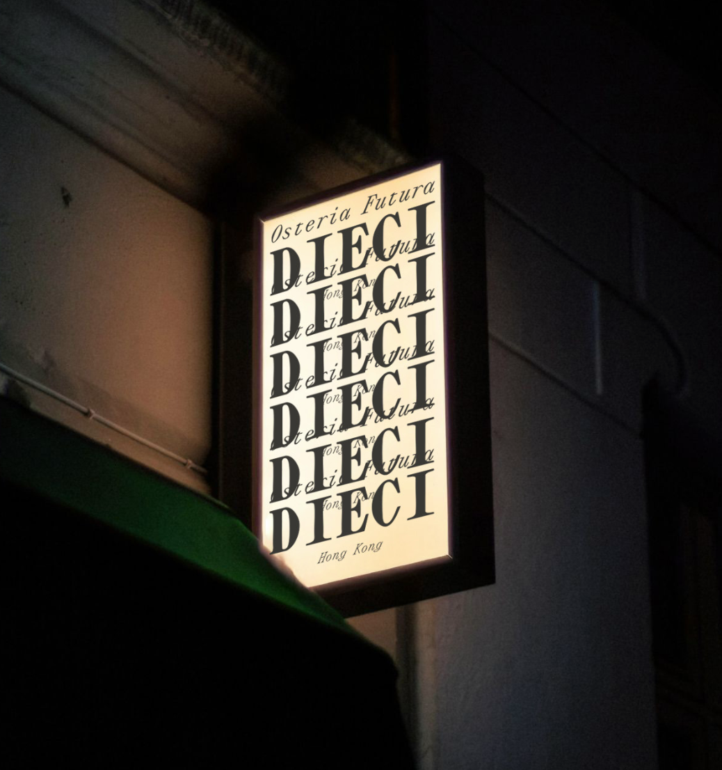 Backlit restaurant sign with the word 'DIEC I' repeated vertically, featuring a handwritten font, and the phrase 'Osteria Futura' at the top and 'Hong Kong' at the bottom.