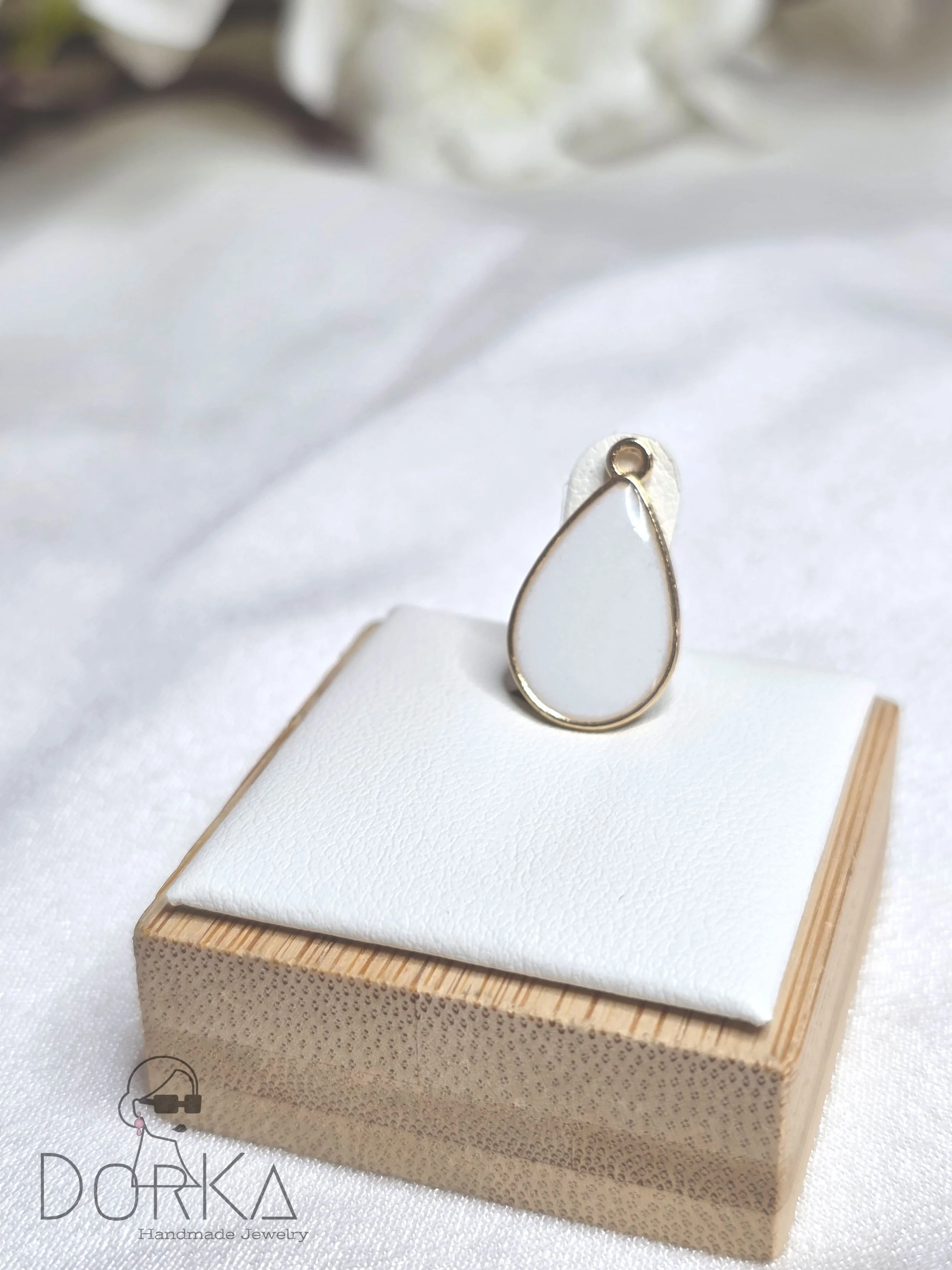 Eine weiße und goldene Perlenohrring auf einem weißen Stoff und Holzbox