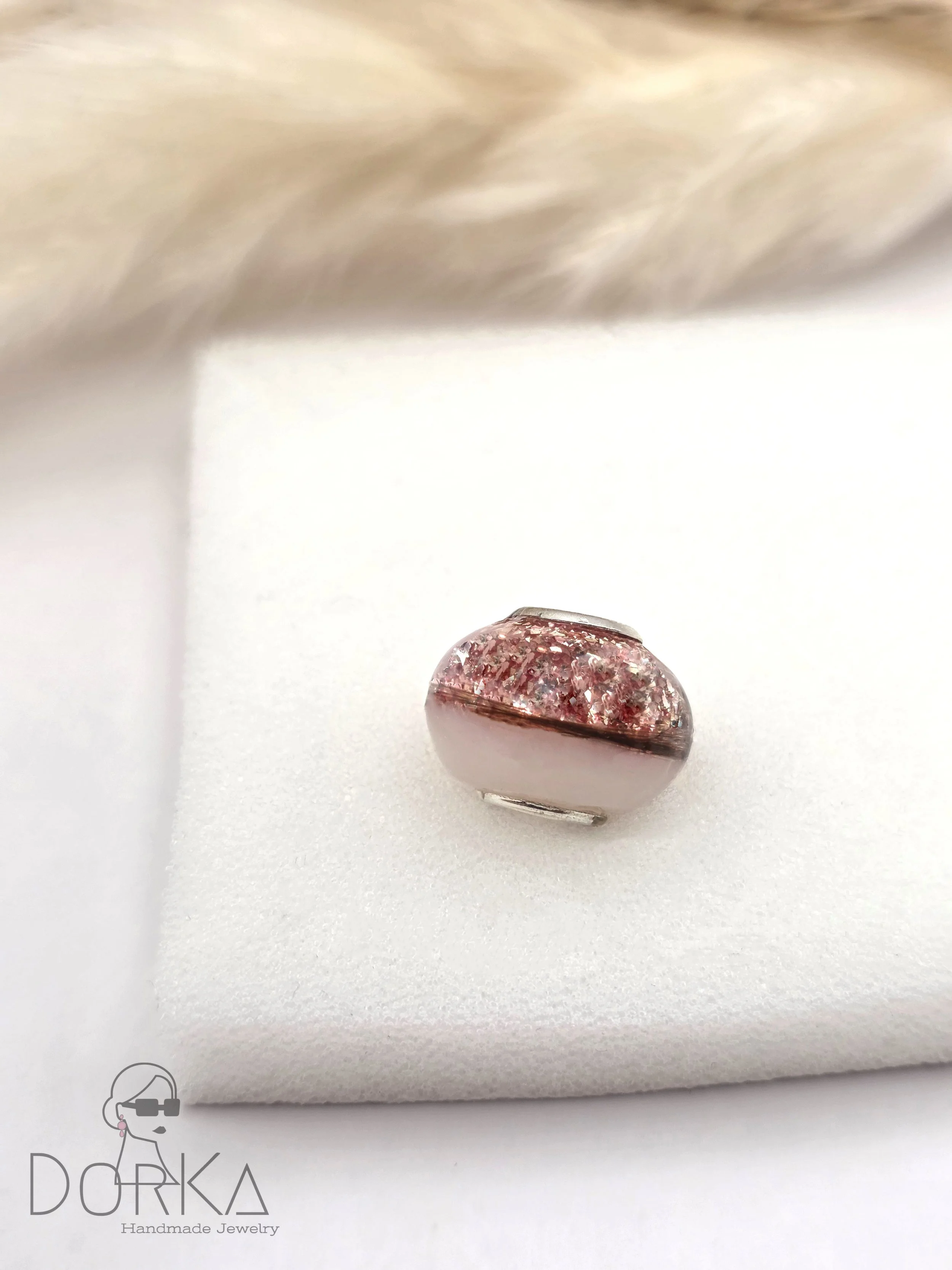 Rosenquarzring mit rosa Kristallen auf weißem Schleifmaterial. Logo "DORKA Handmade Jewelry" im unteren linken Eck.