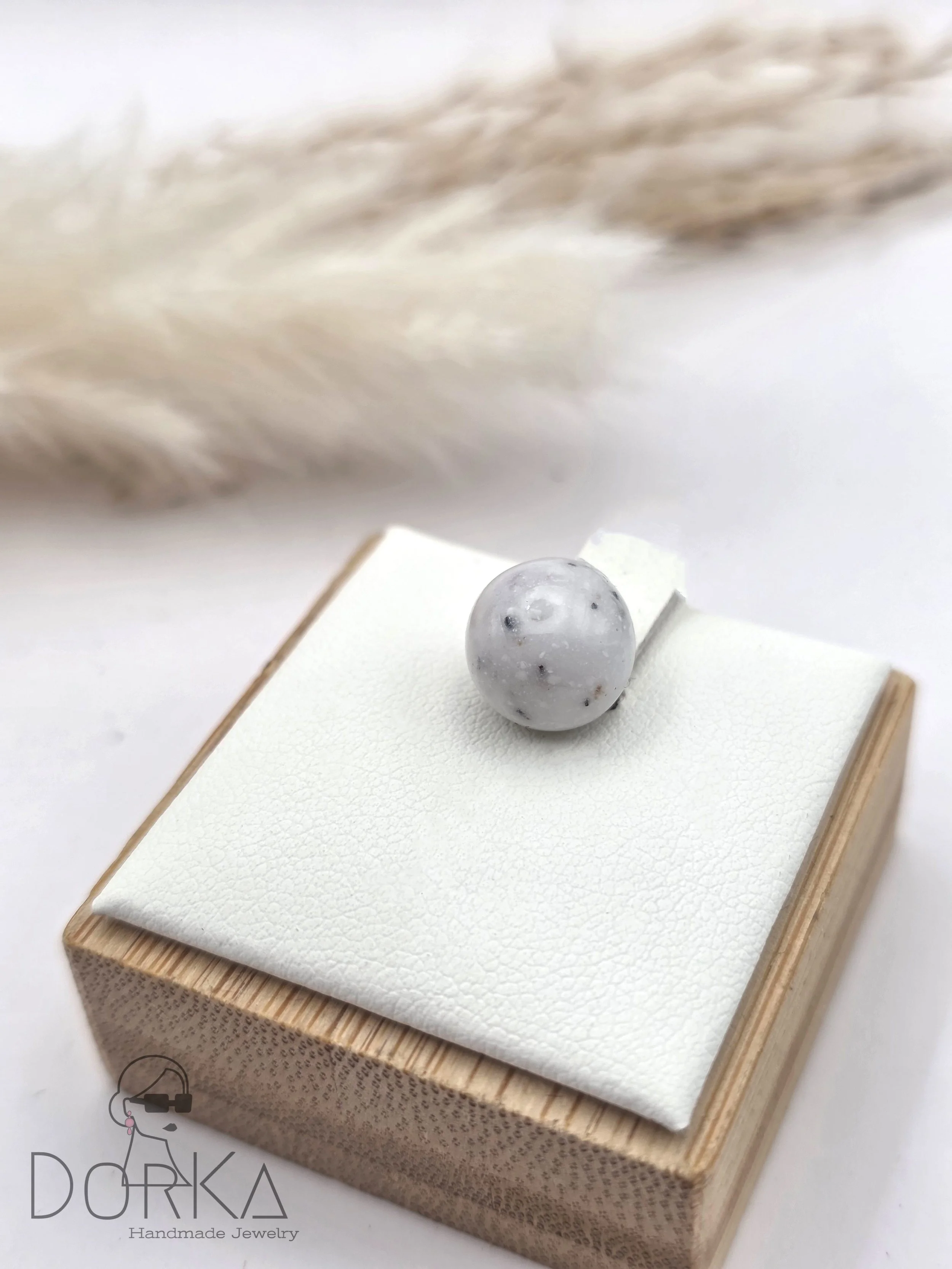 Handgefertigter Schmuck von Dorka Jewelry, eine weiße Perle auf schwarzem Untergrund, präsentiert auf einer weißen und Holz-Box