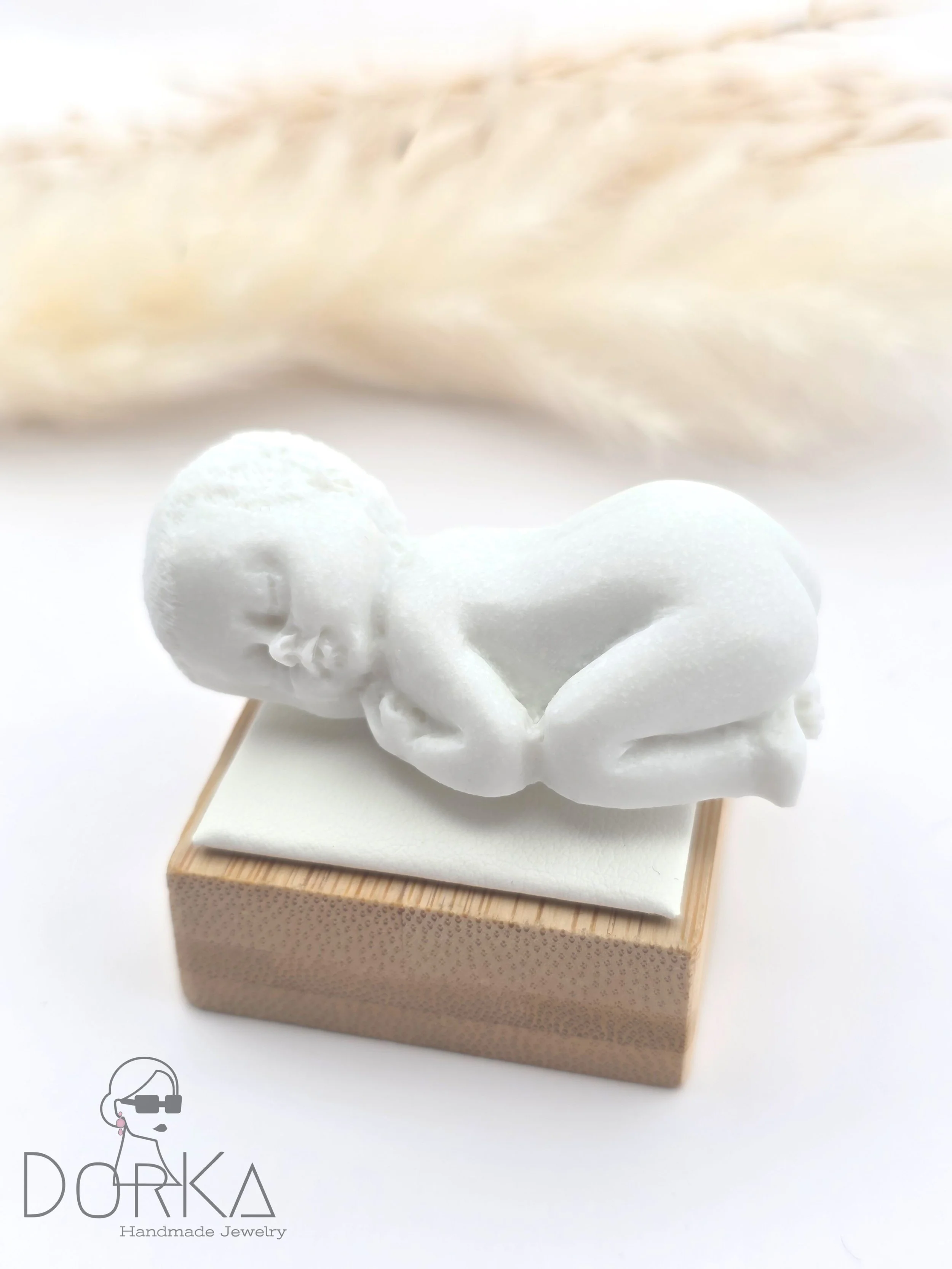 Kleines weißes Baby aus Styropor liegt auf einem weißen Untergrund, hinter einem großen weißen Fellteppich.